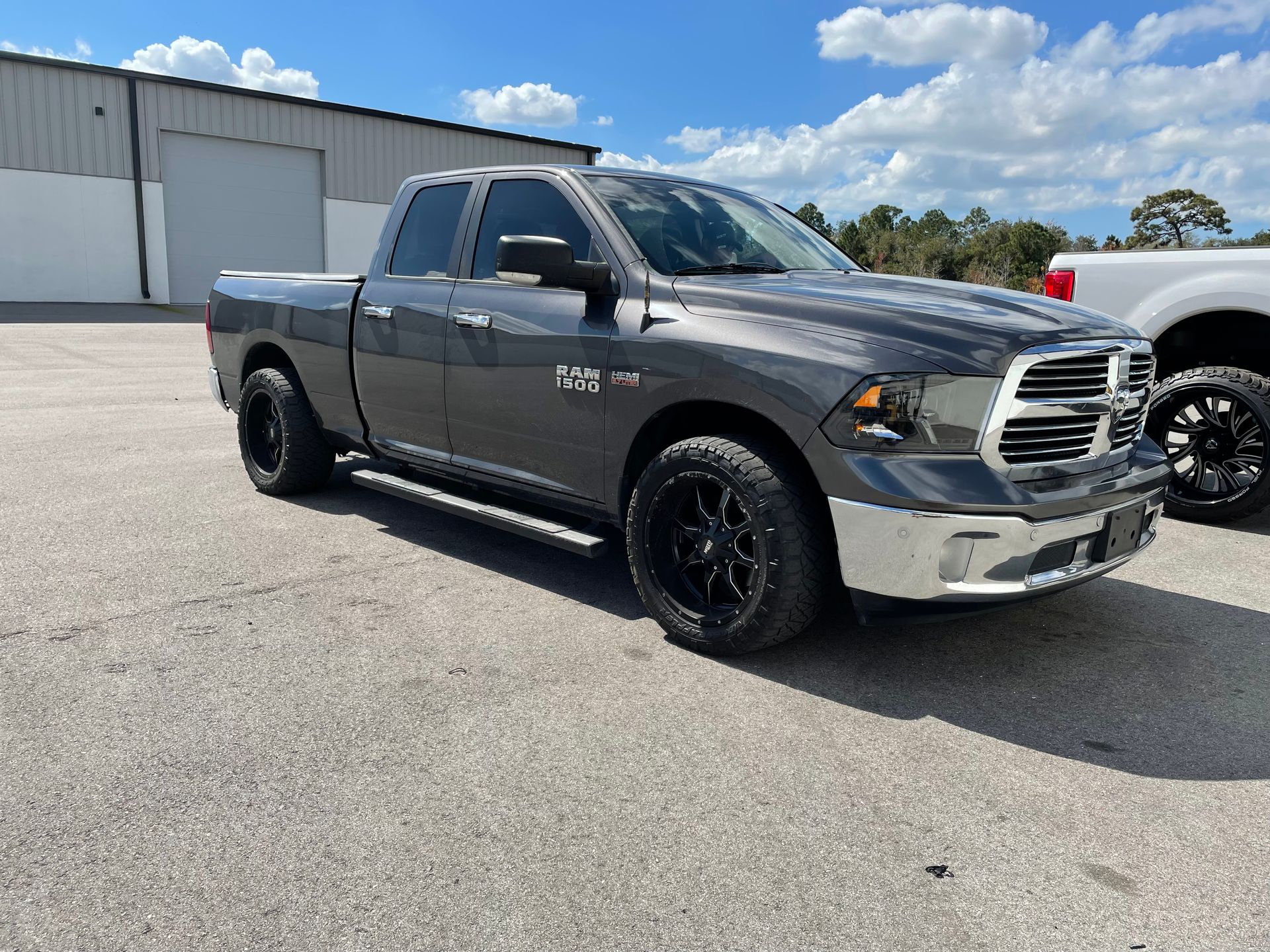 A gray dodge ram 1500 truck is parked in a parking lot.