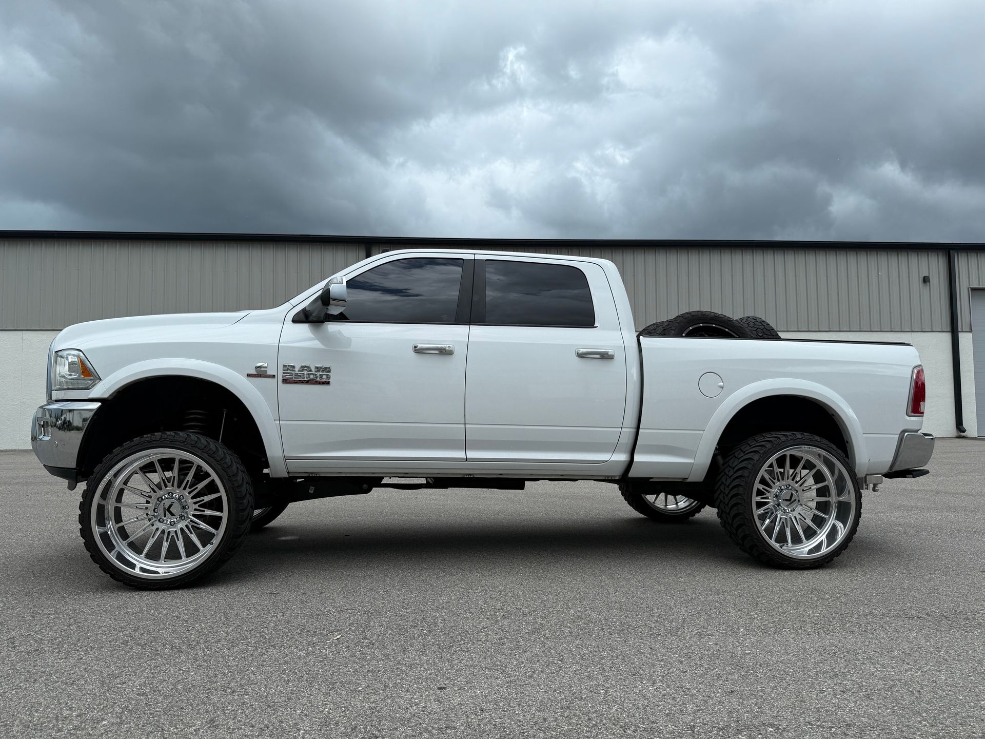 A white dodge ram truck is parked in front of a building.