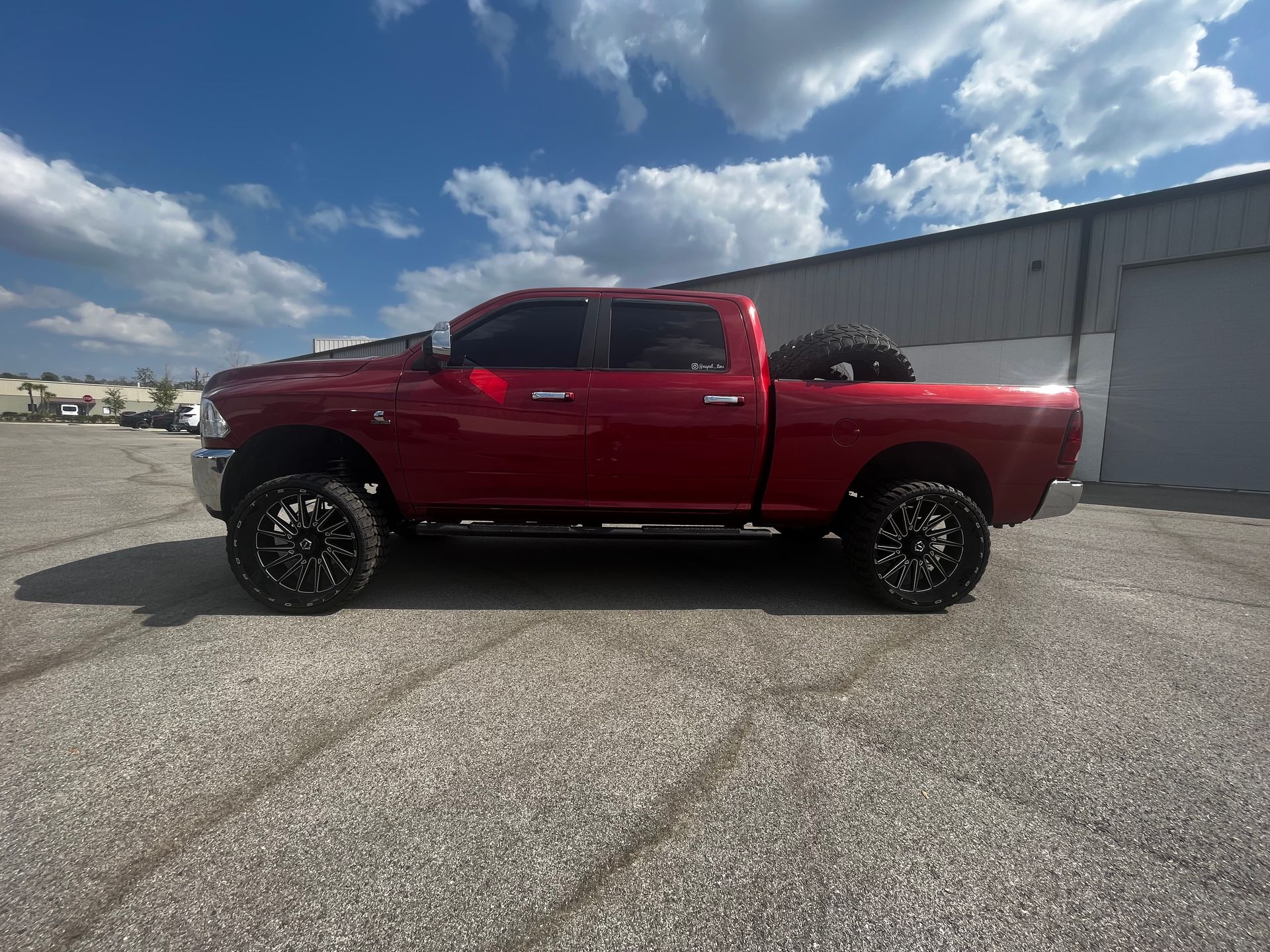 A red truck is parked in a parking lot in front of a building.