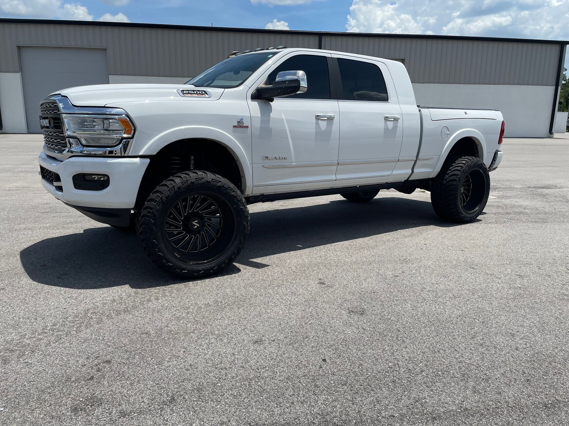 A white dodge ram truck is parked in front of a building.