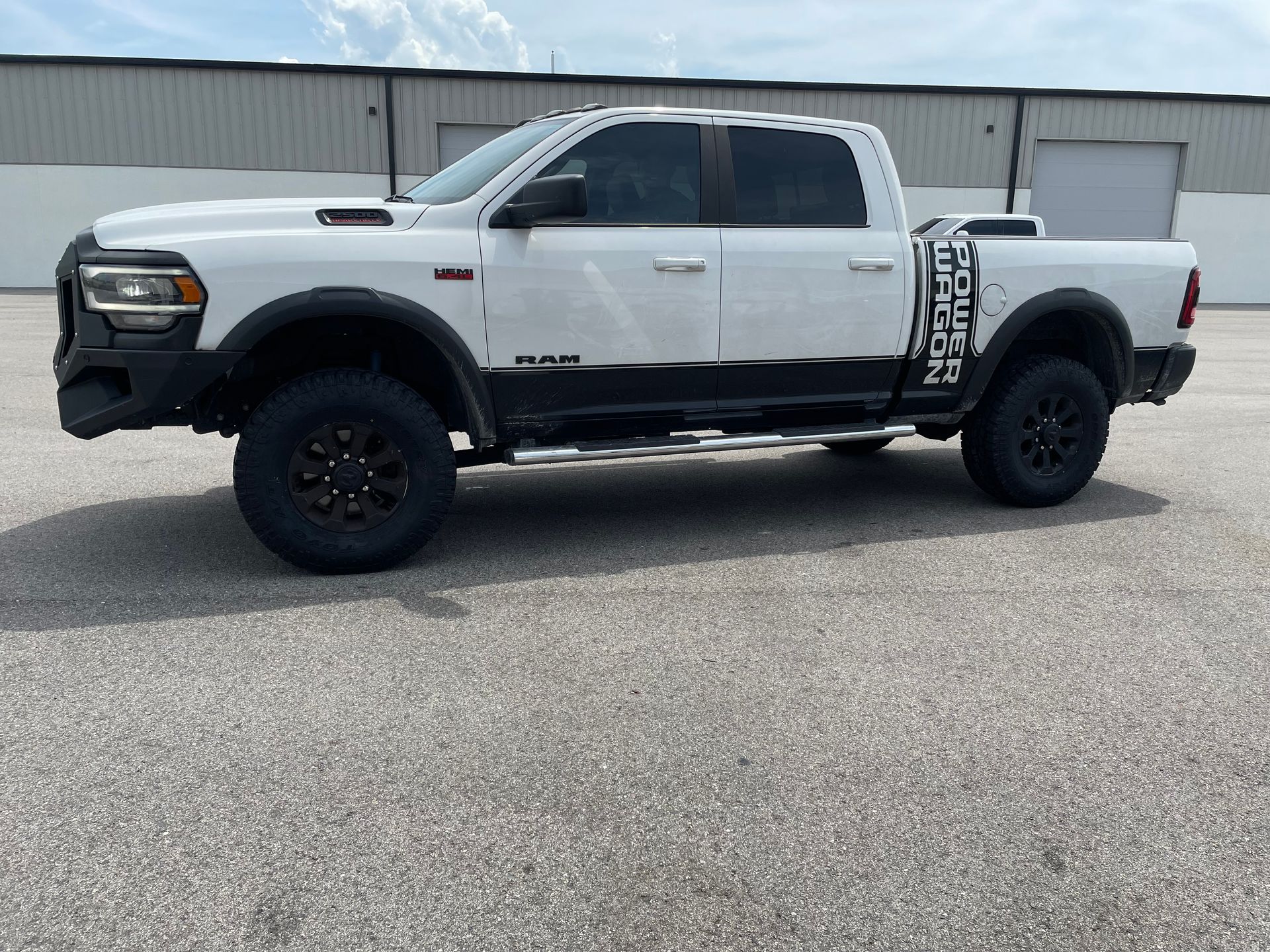 A white truck is parked in a parking lot in front of a building.