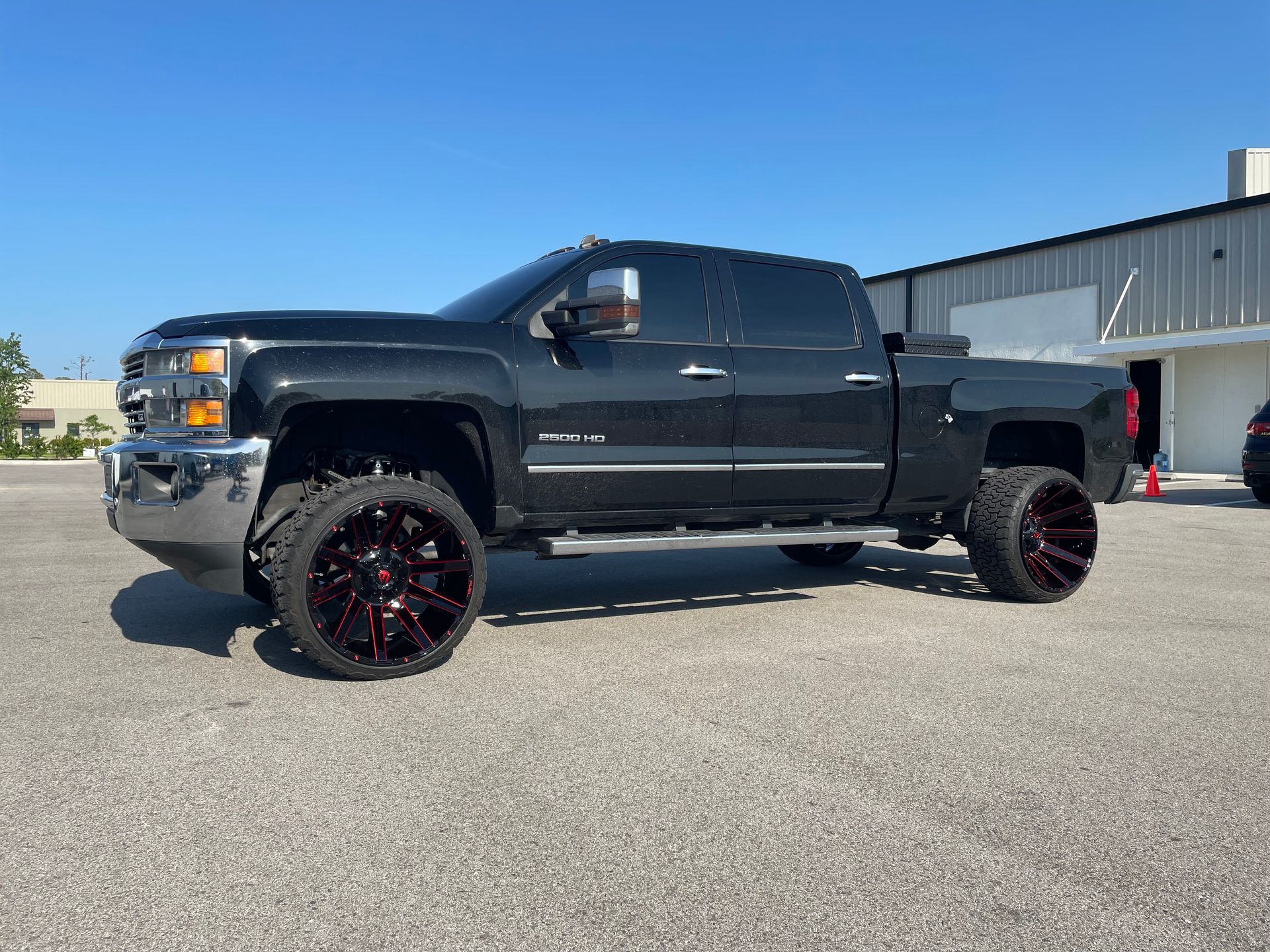 A black truck is parked in a parking lot in front of a building.