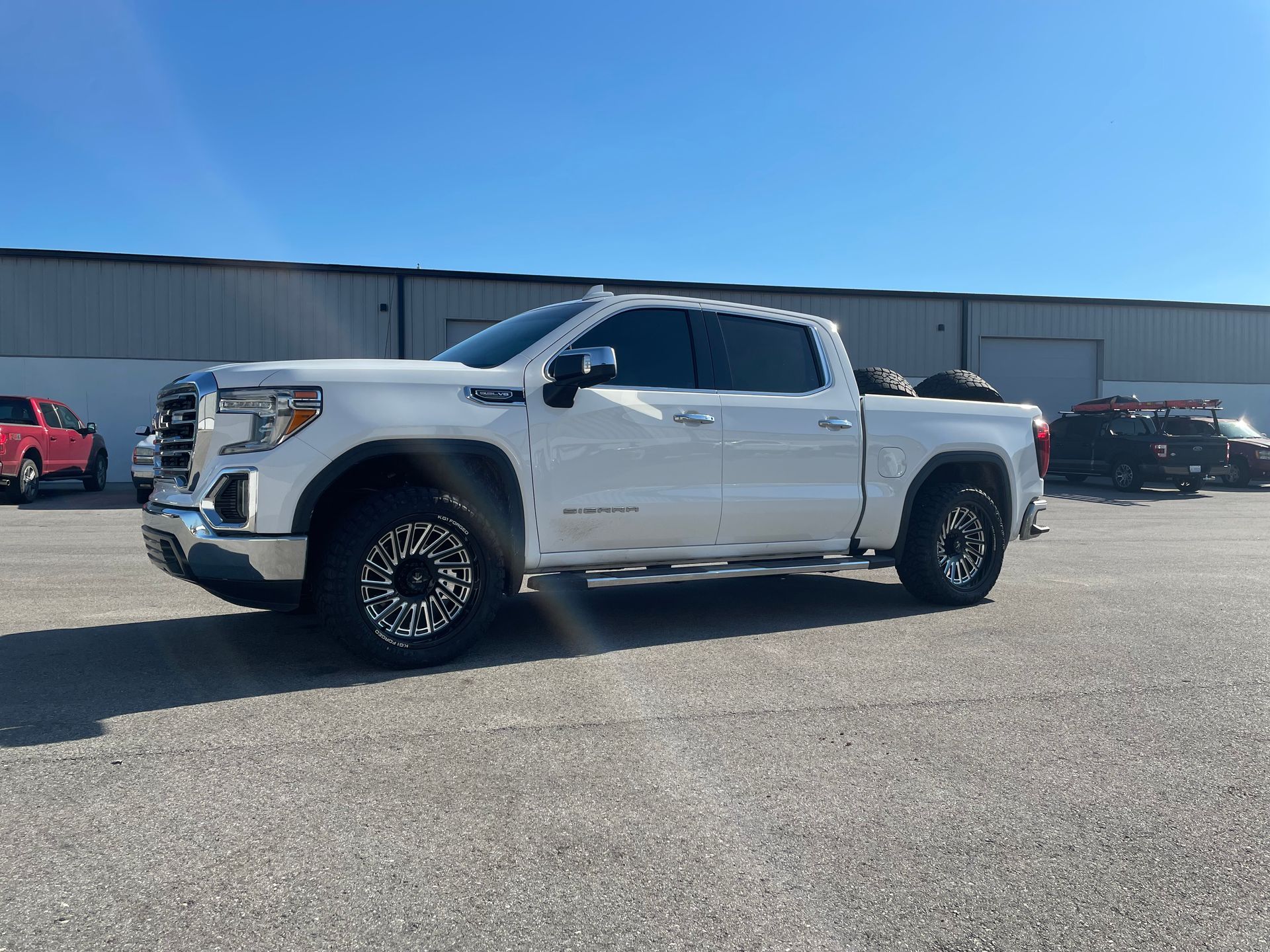 A white truck is parked in a parking lot in front of a building.