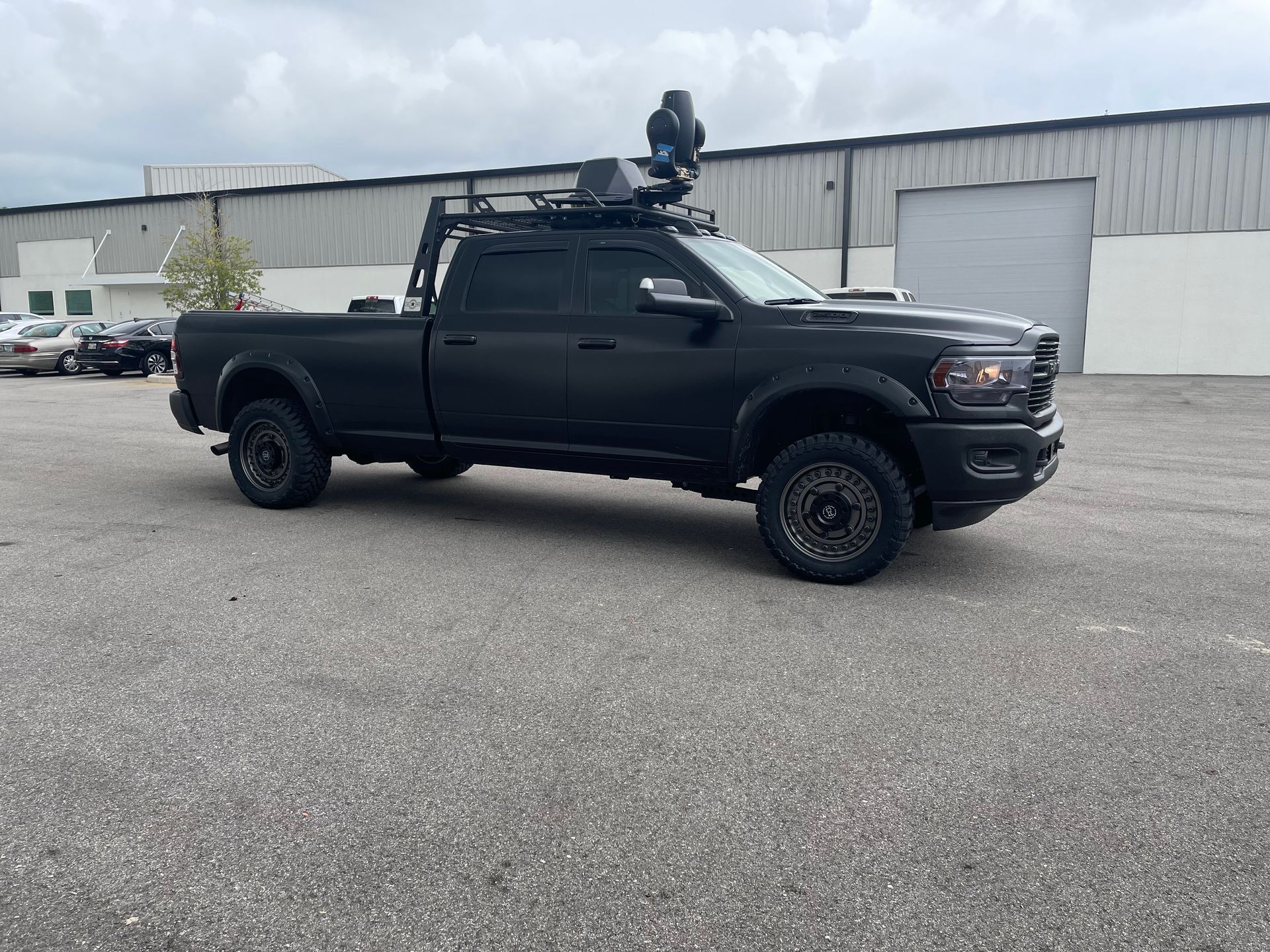 A black truck with a roof rack is parked in a parking lot.