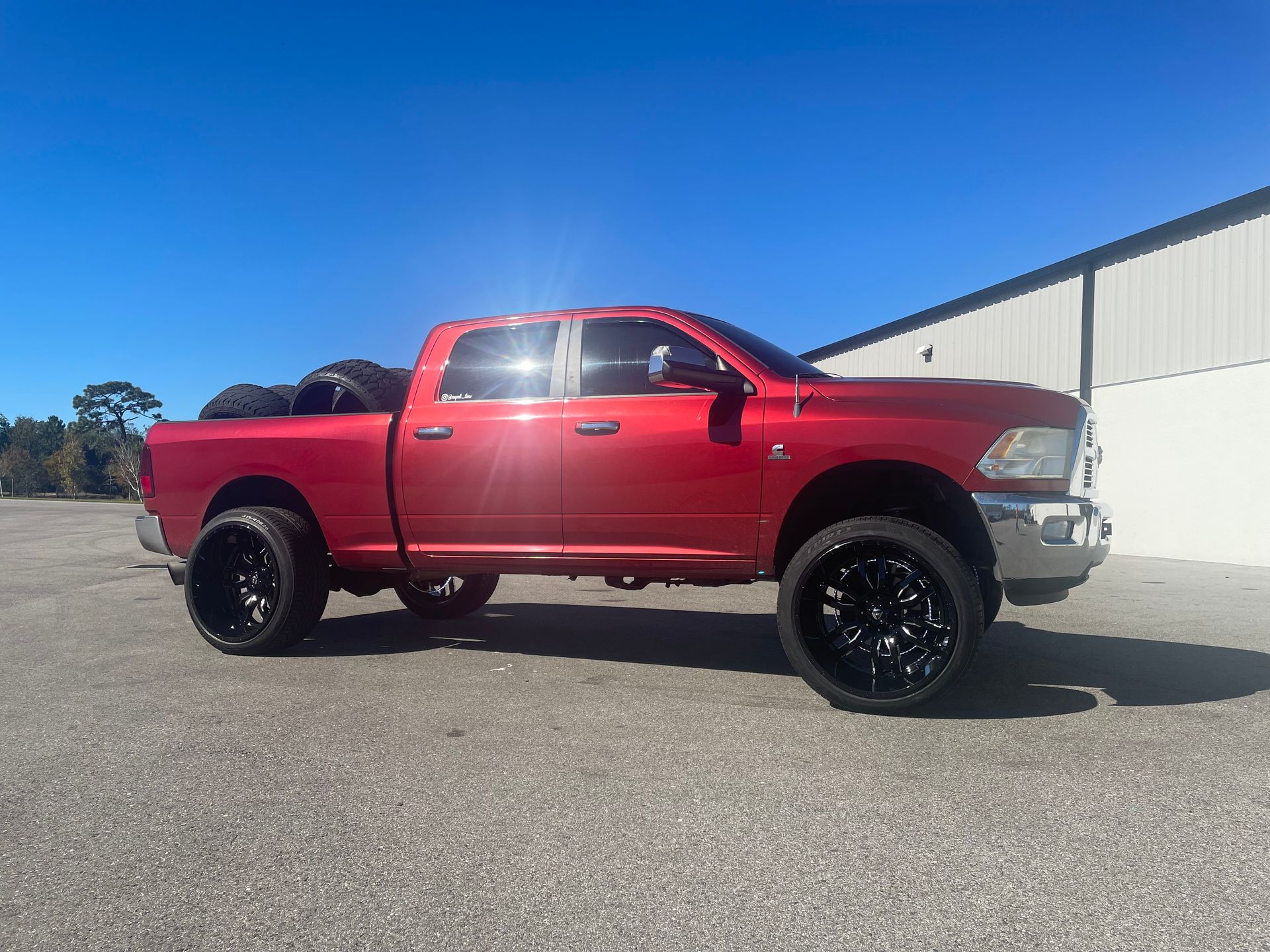 A red dodge ram truck is parked in front of a building.