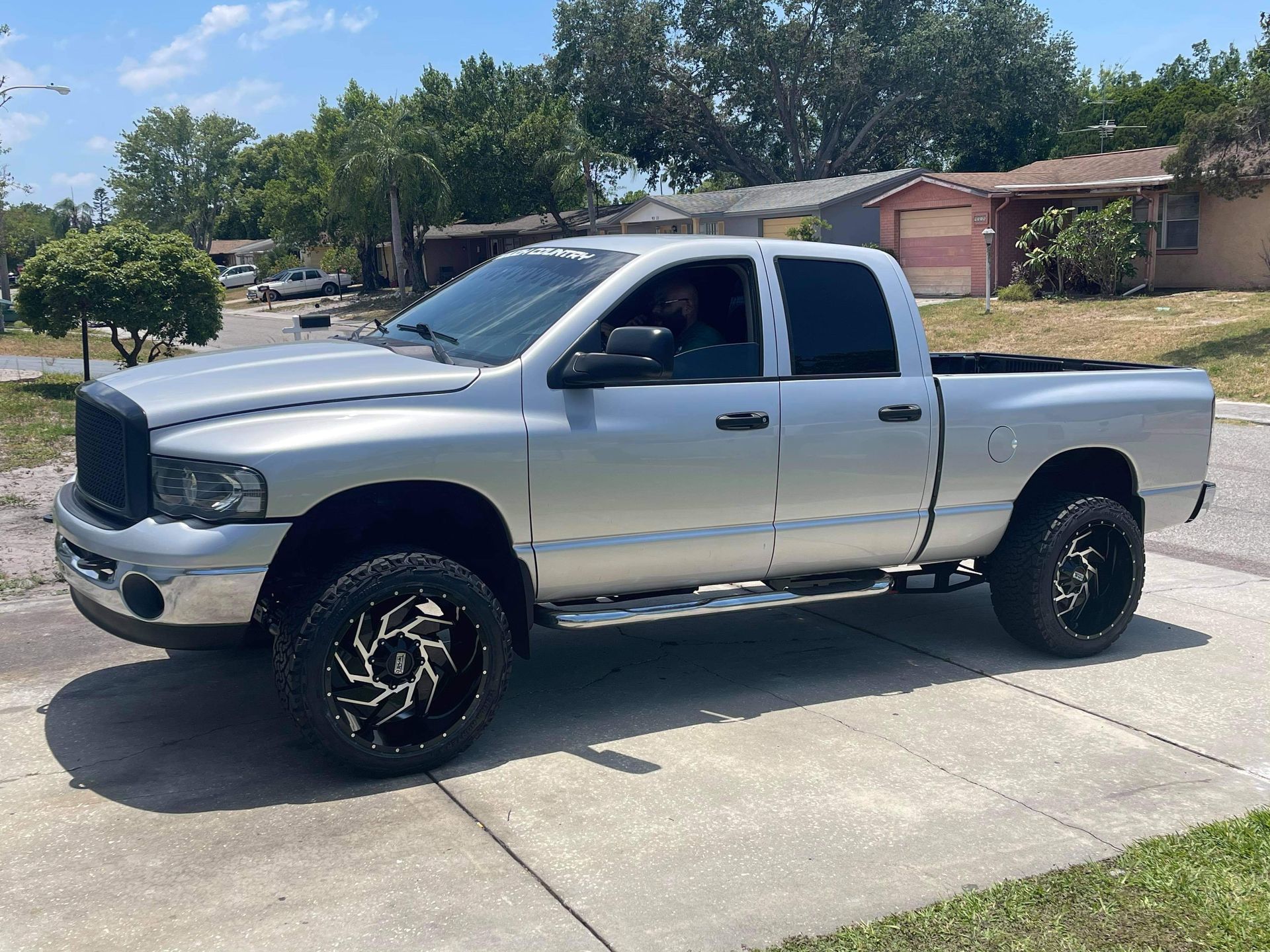 A silver dodge ram truck is parked on the side of the road.