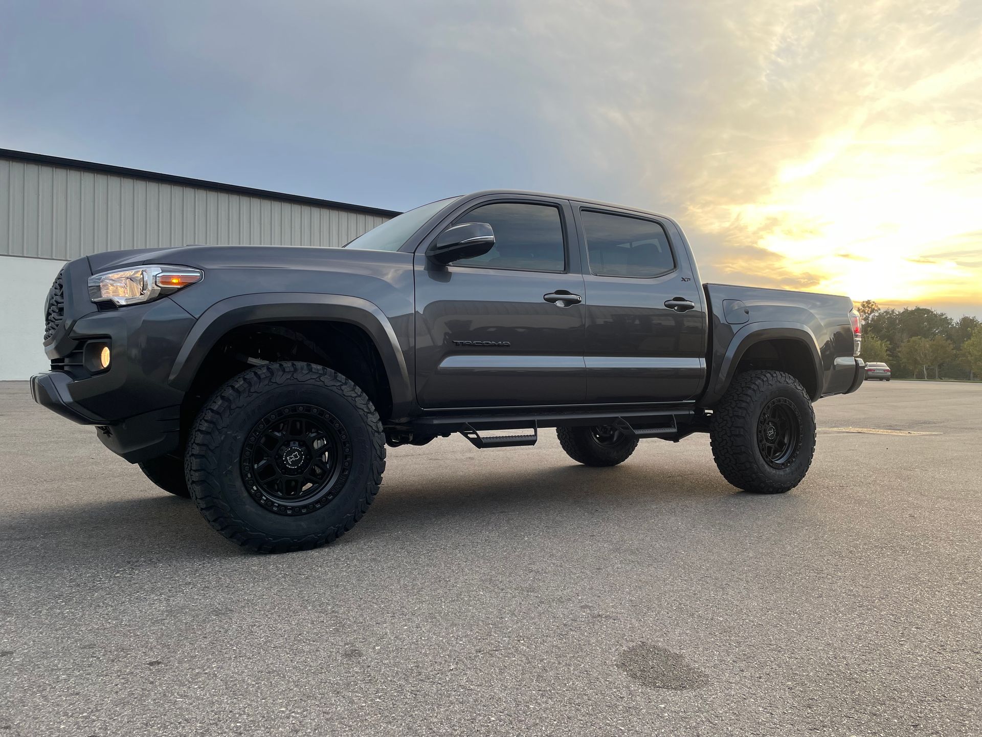 A black toyota tacoma truck is parked in a parking lot.