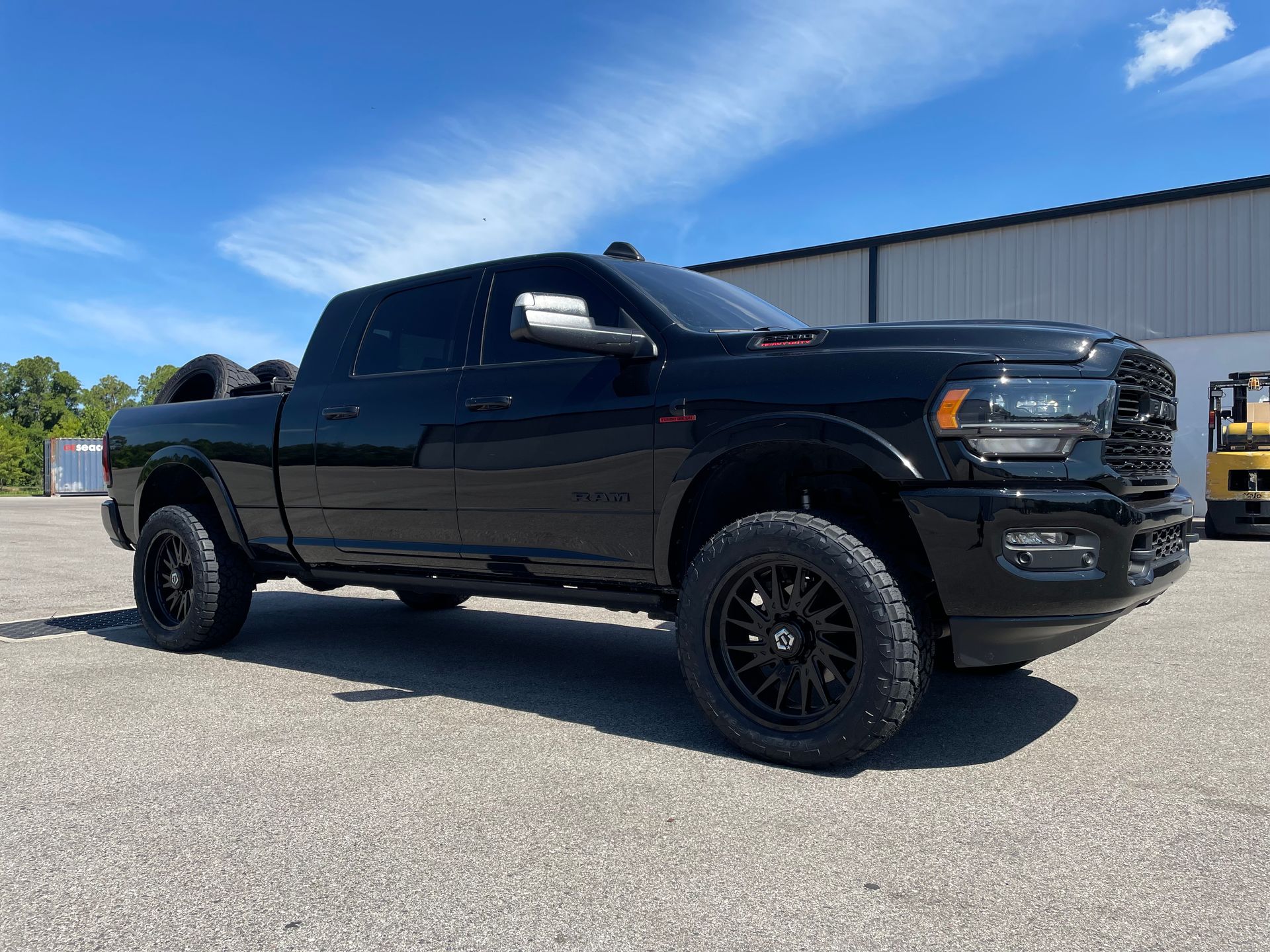 A black dodge ram truck is parked in a parking lot in front of a building.