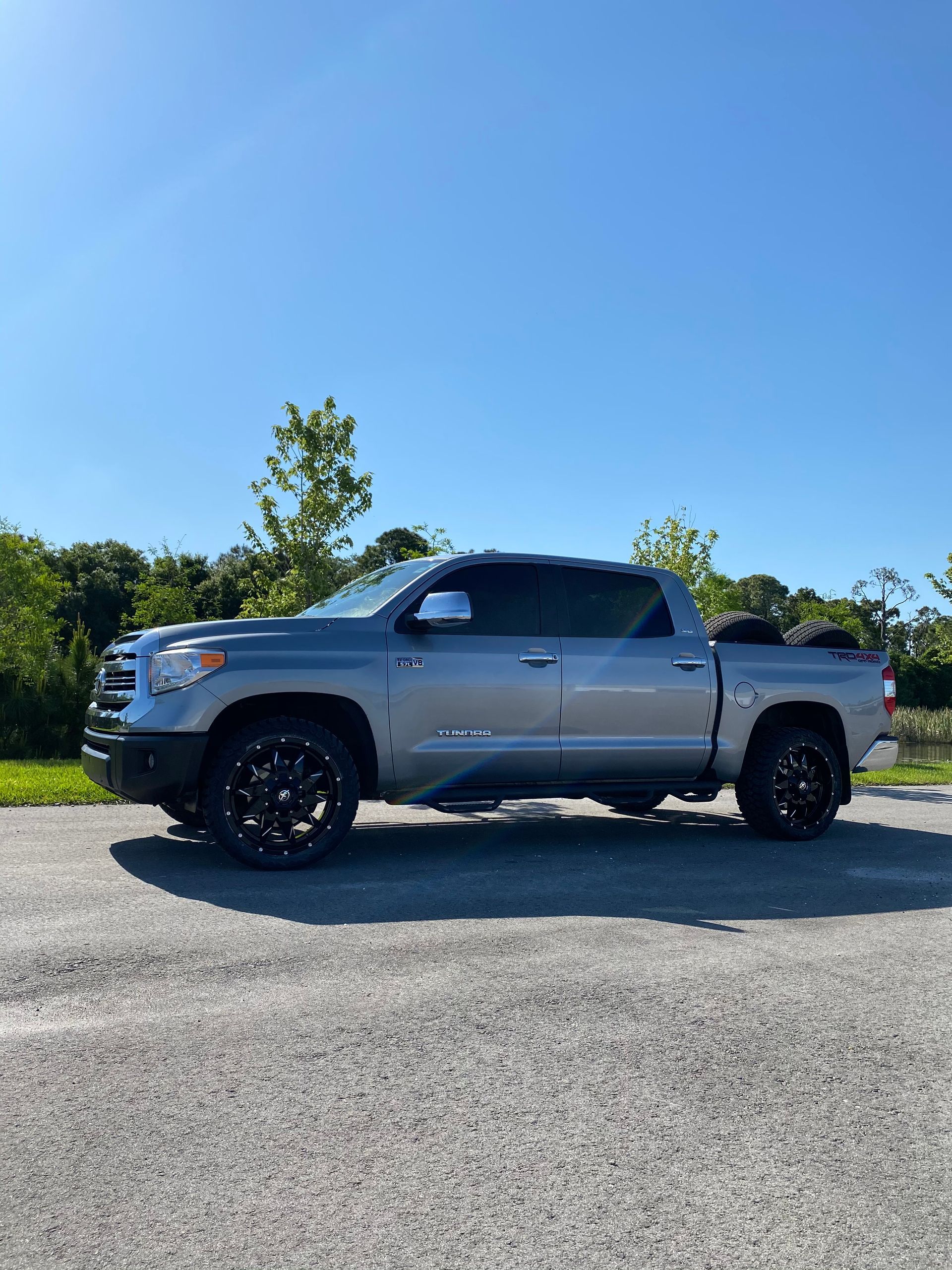 A silver toyota tundra is parked in a gravel lot.