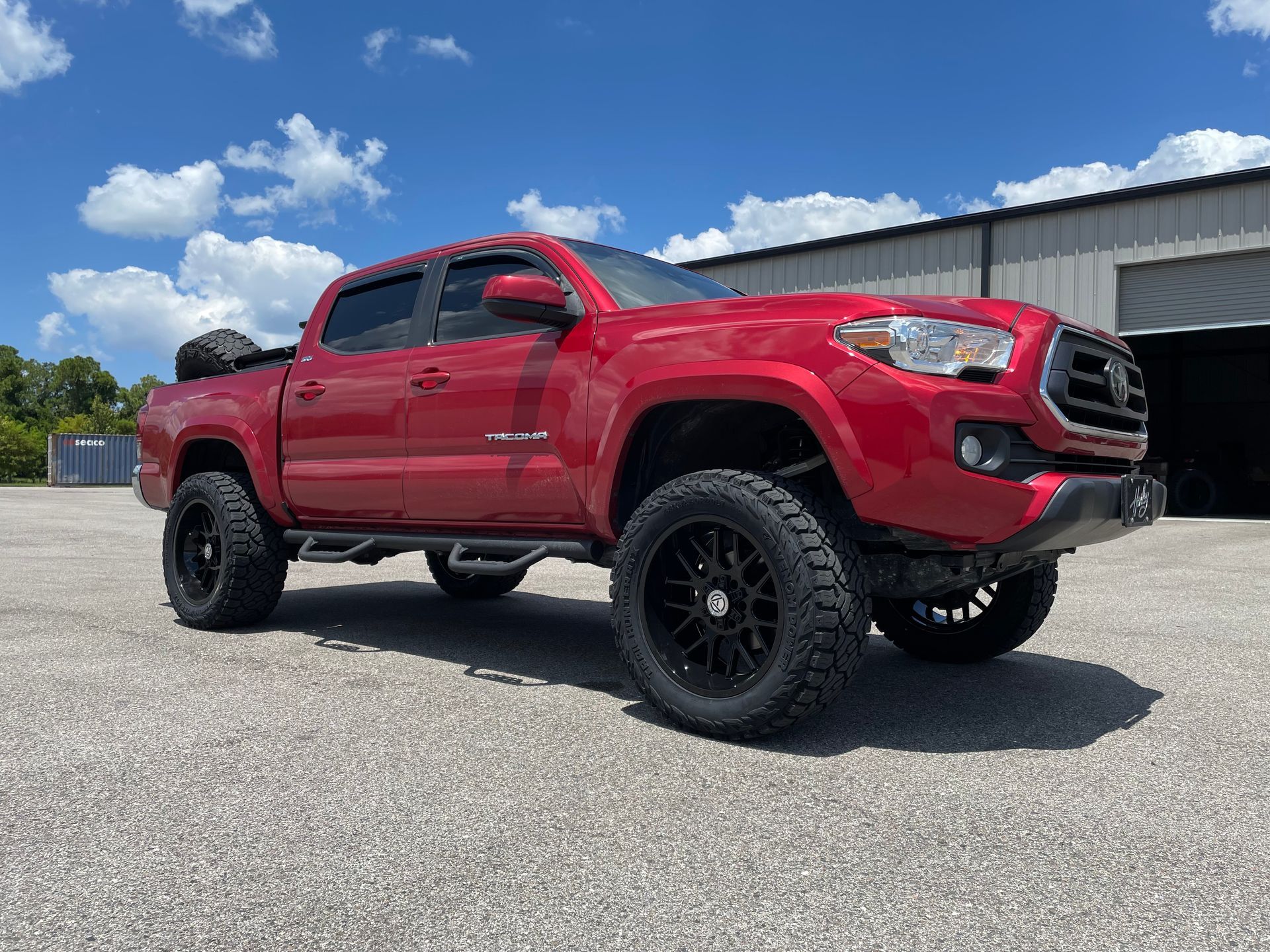 A red toyota tacoma truck is parked in front of a building.