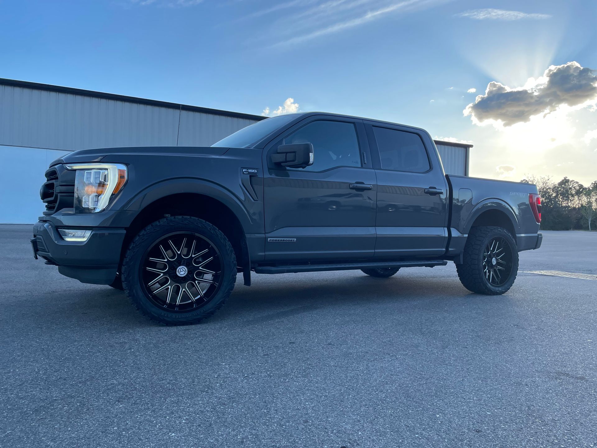 A black ford f150 truck is parked on the side of the road in front of a building.