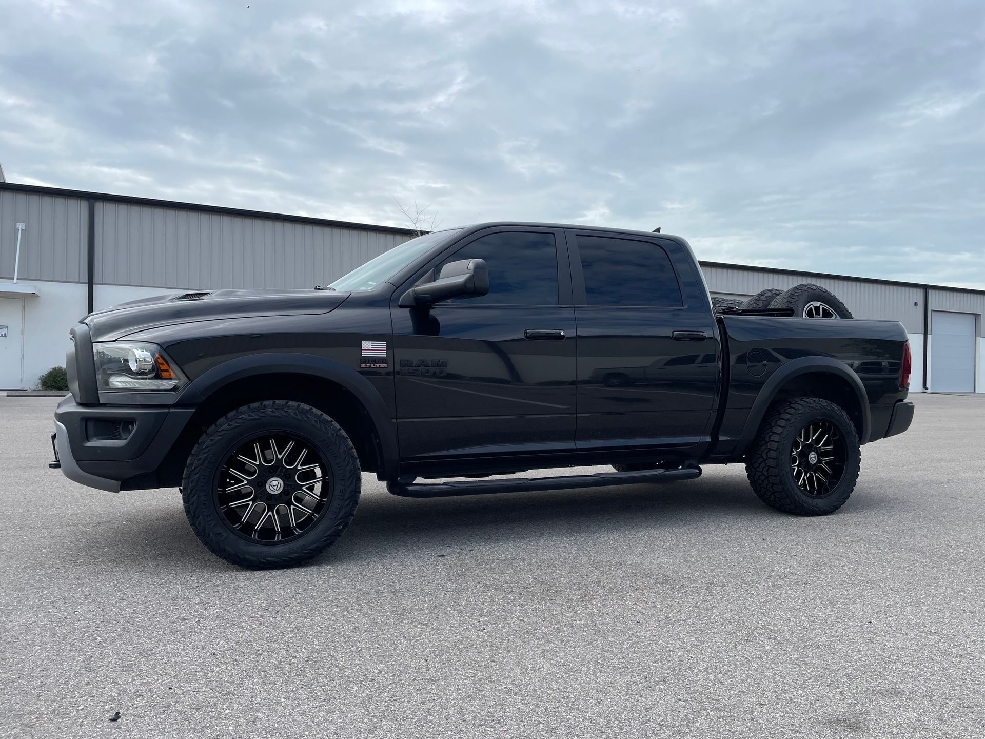 A black dodge ram truck is parked in front of a building.