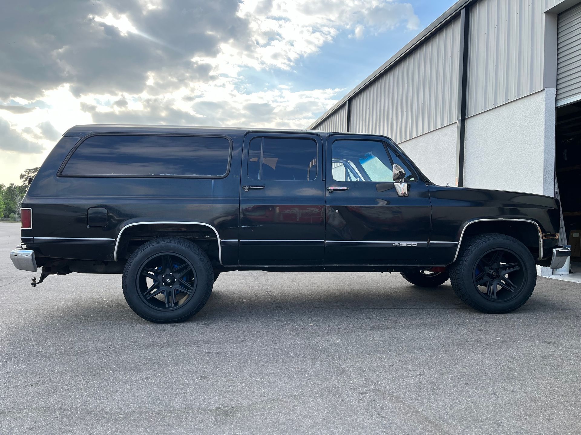 A black chevrolet suburban is parked in front of a building.