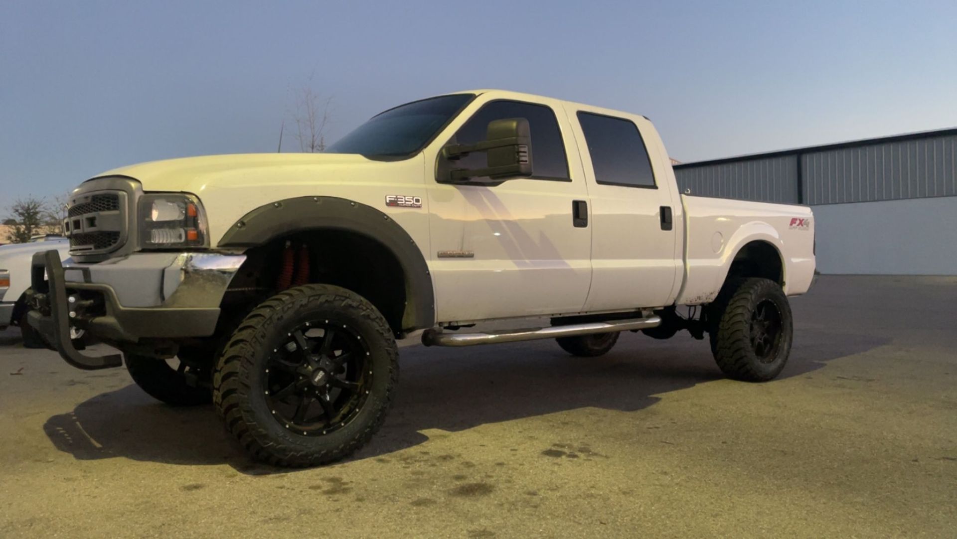 A white truck with black wheels is parked in a parking lot.