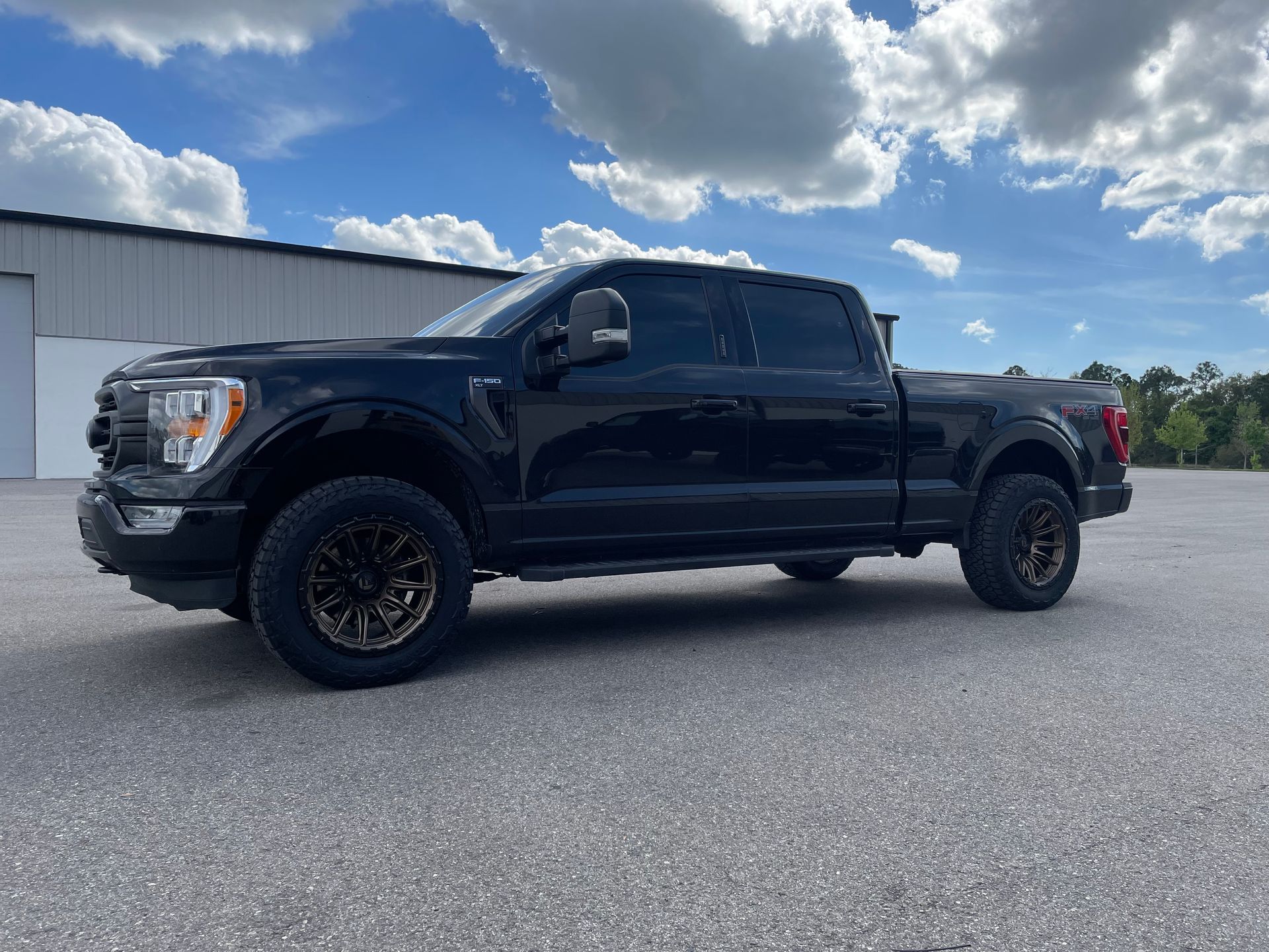 A black pickup truck is parked in a parking lot in front of a building.
