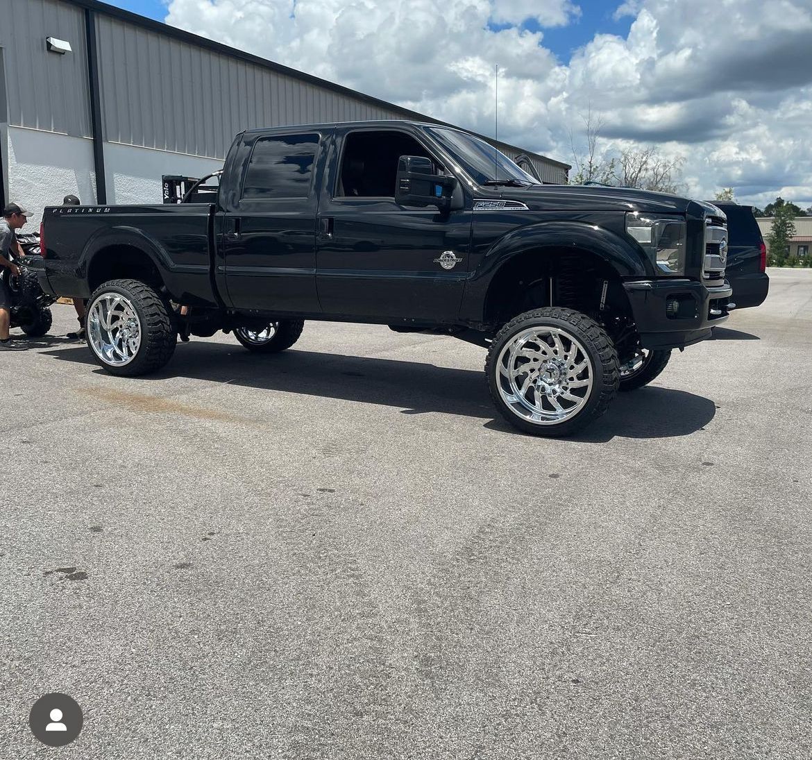 A black truck is parked in a parking lot in front of a building.