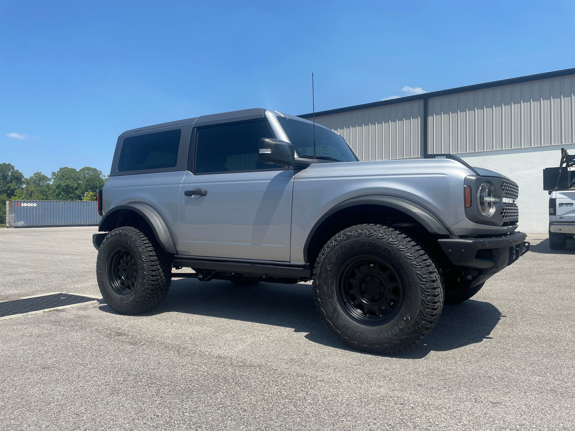 A silver ford bronco is parked in a parking lot in front of a building.