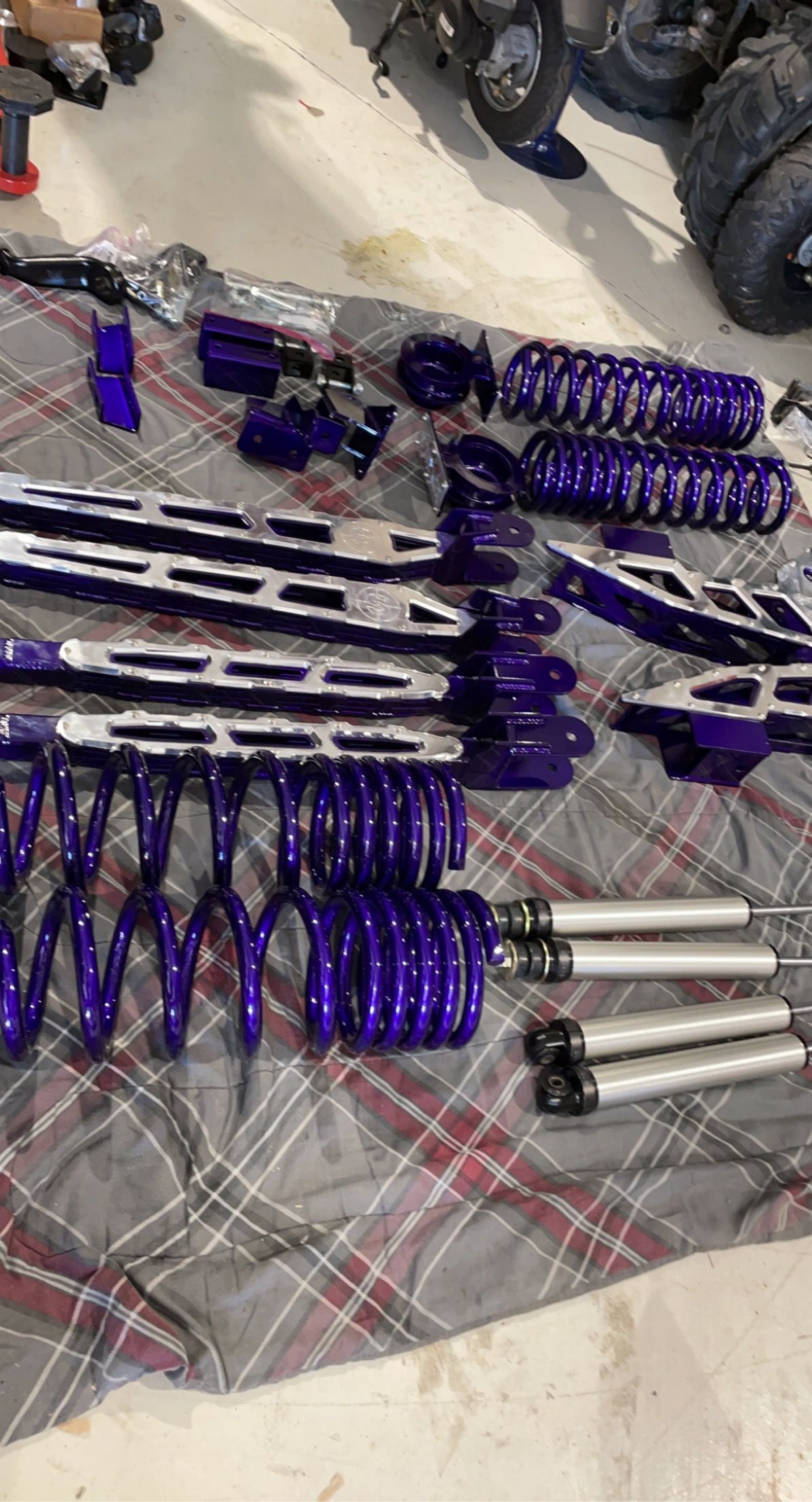 A bunch of purple suspension parts are sitting on top of a plaid cloth.