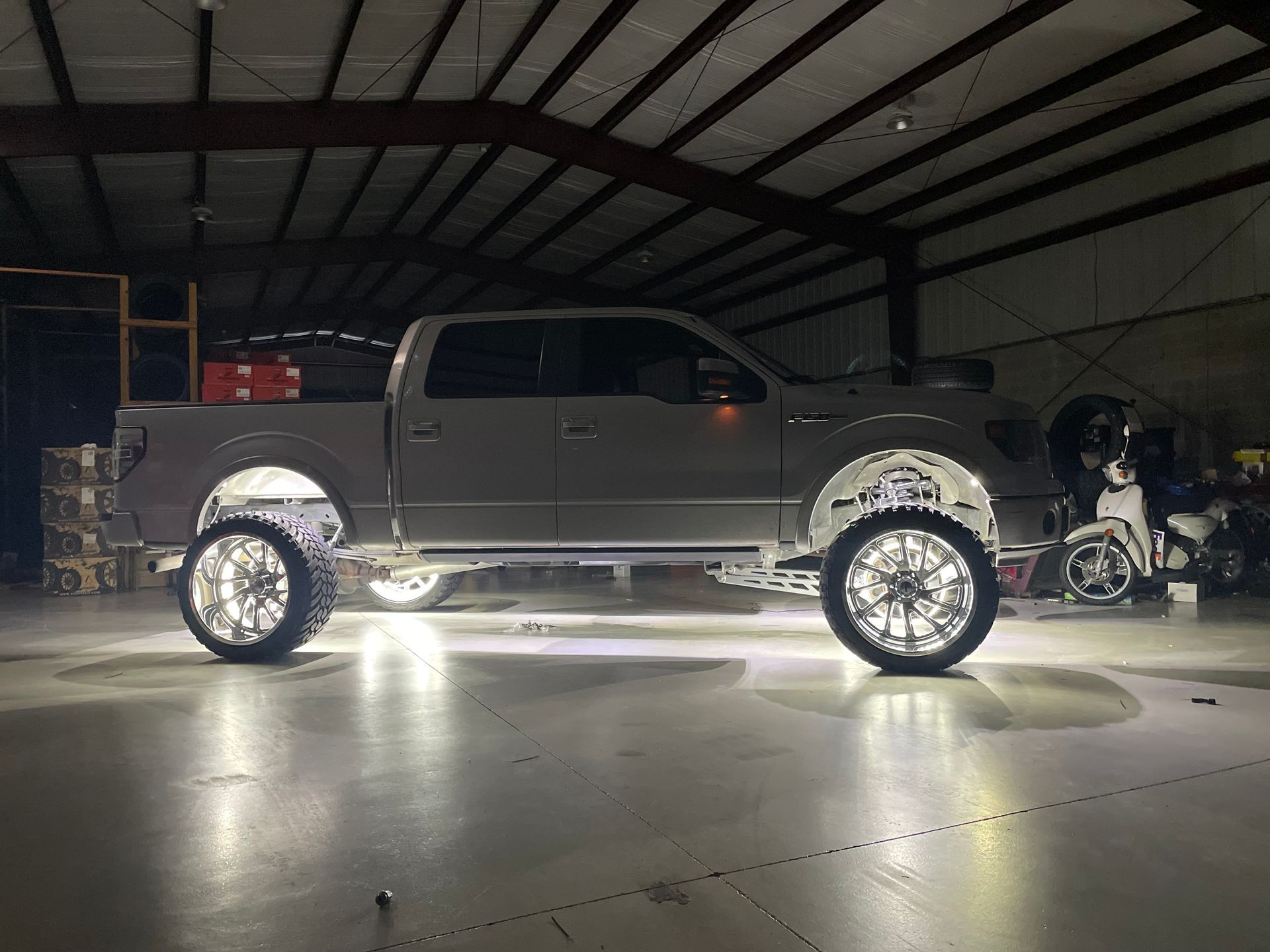 A truck is parked in a garage with lights on the wheels.
