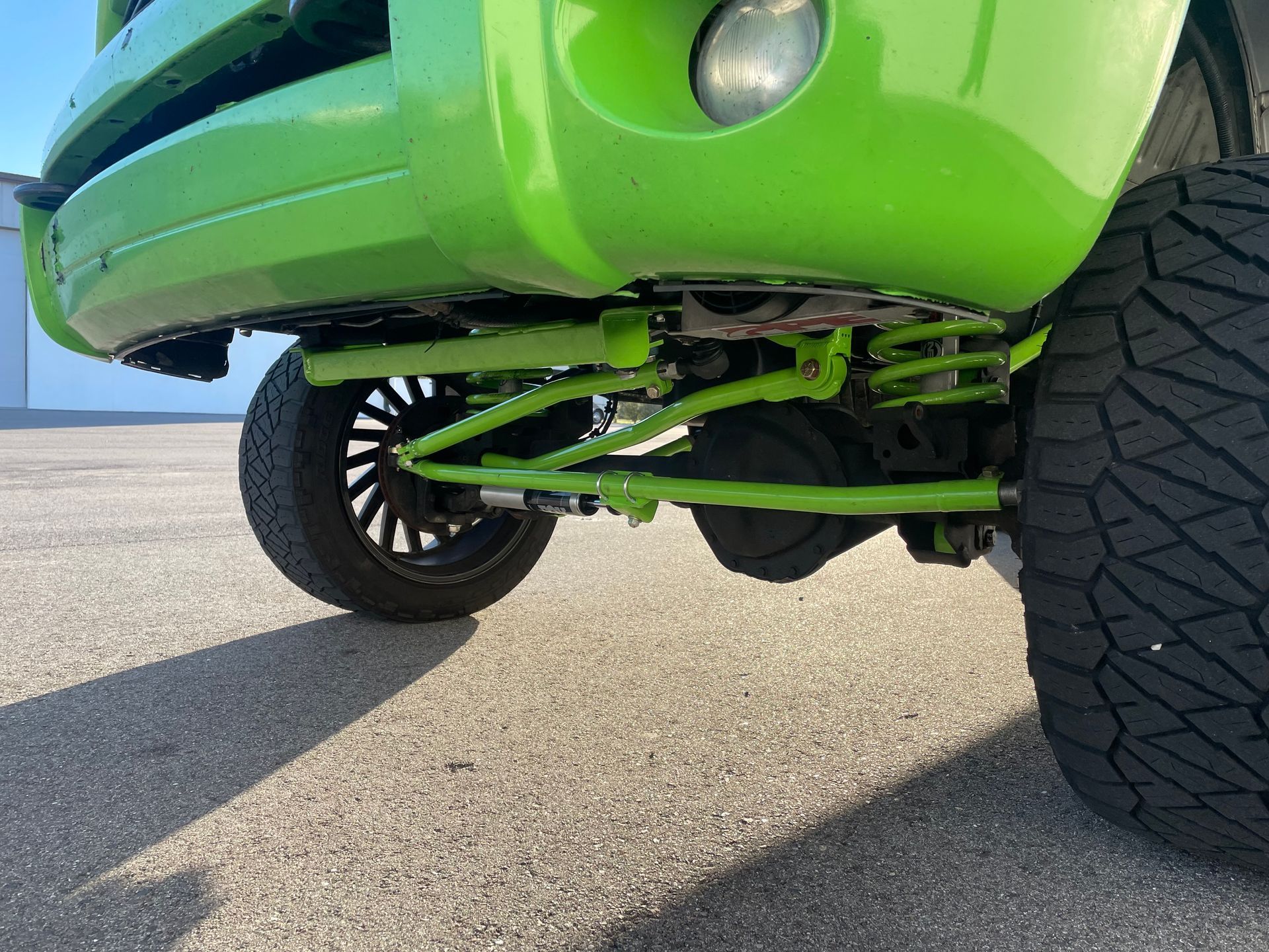 A green truck is parked on the side of the road.