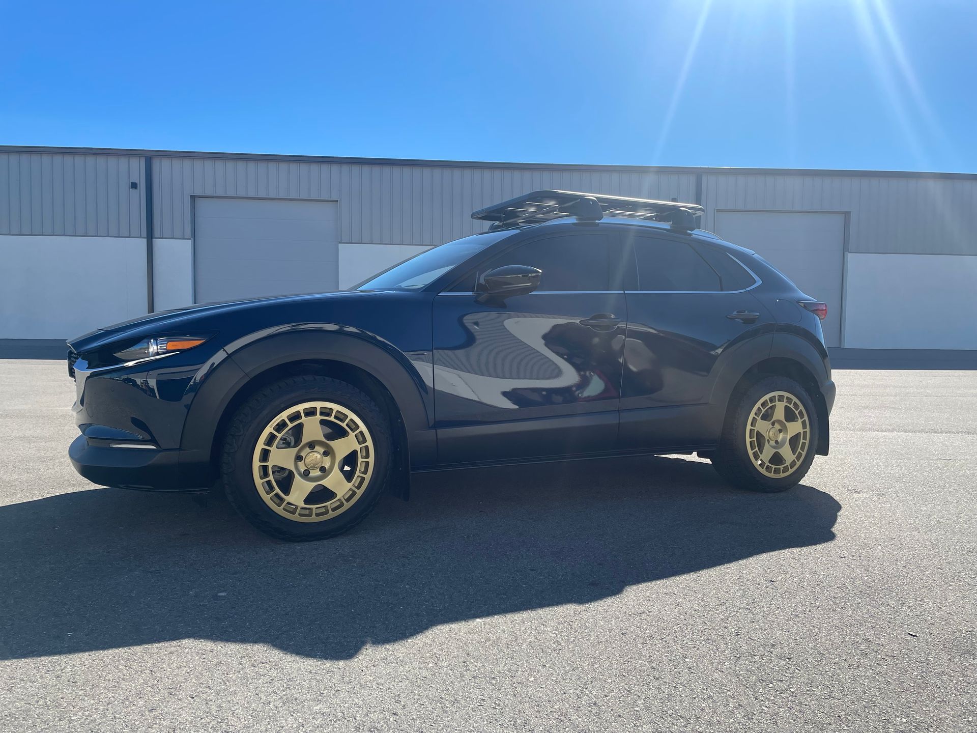 A black car with gold wheels is parked in front of a building.