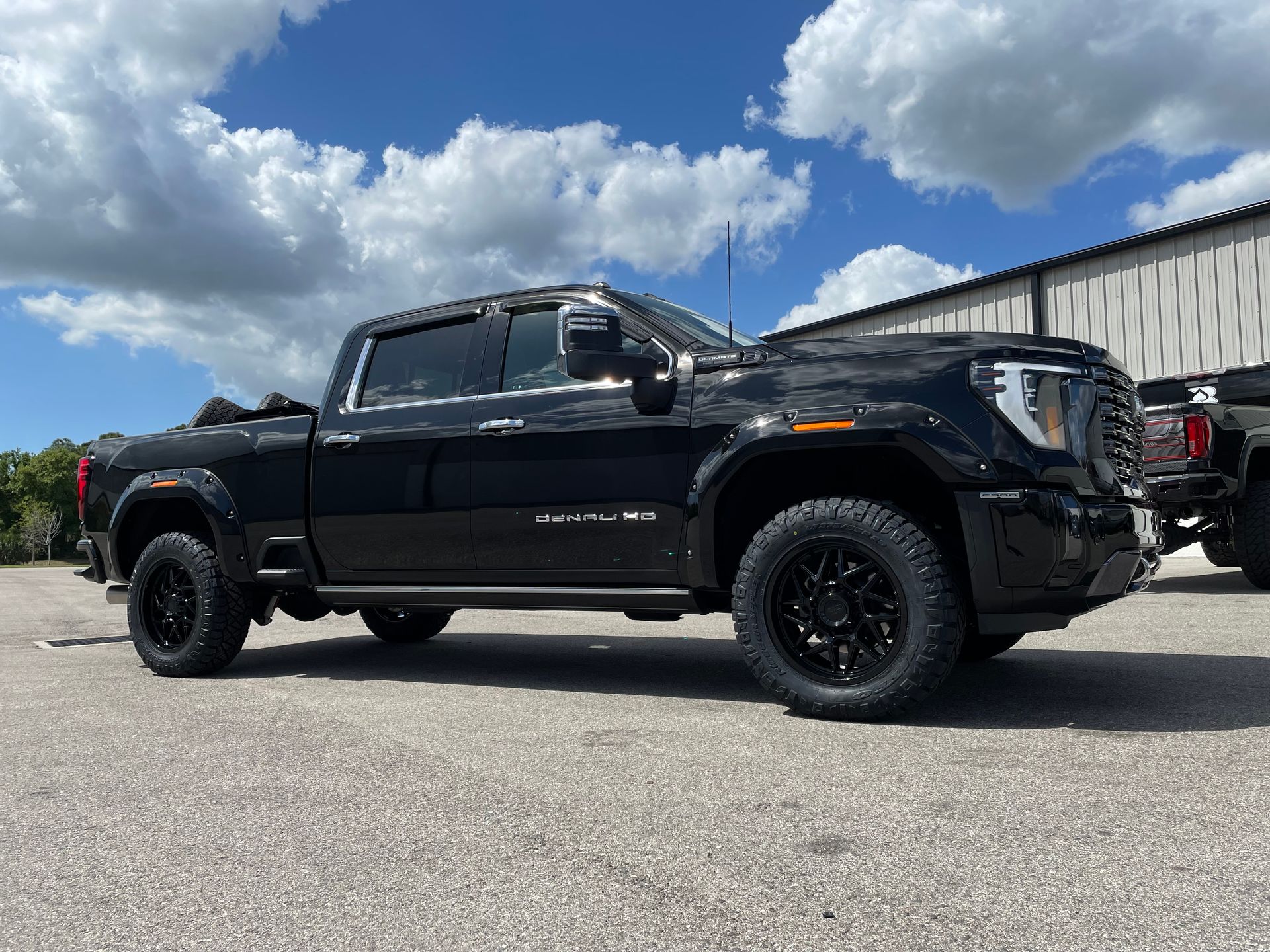 A black pickup truck is parked in a parking lot in front of a building.