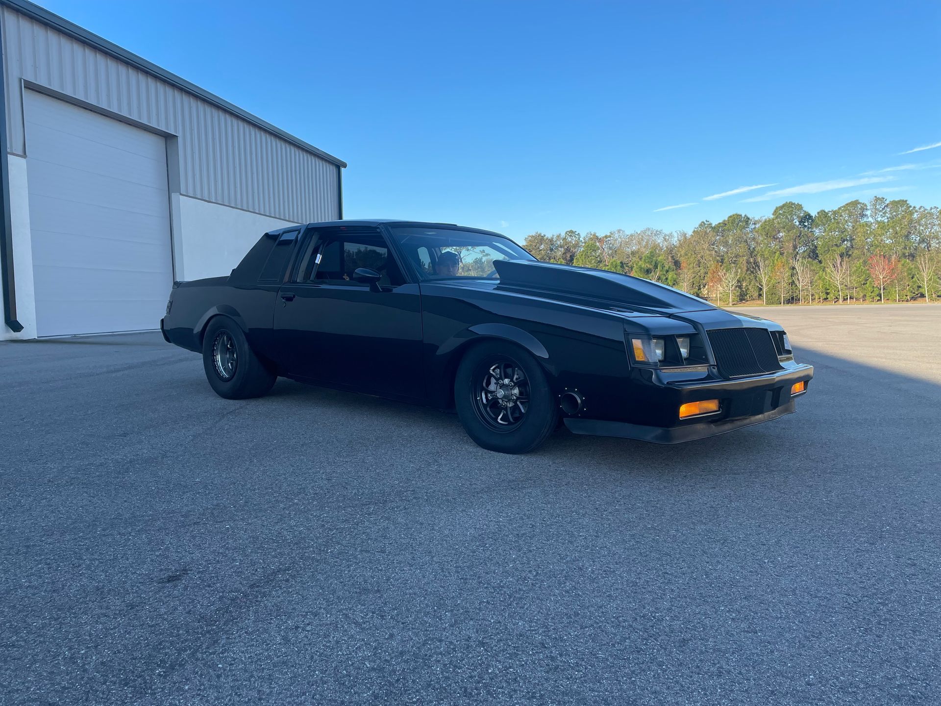 A black car is parked in front of a garage.