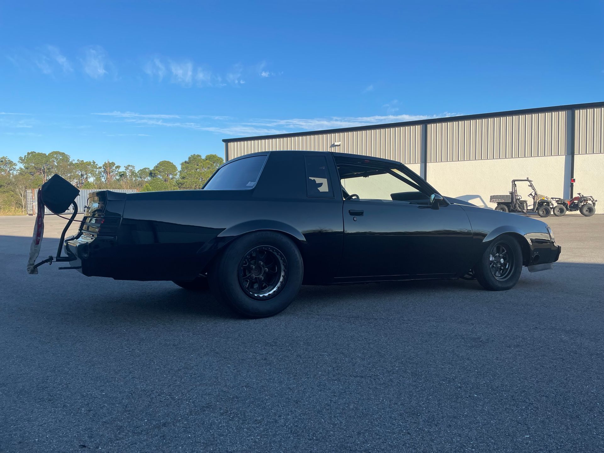 A black truck is parked in a parking lot in front of a building.