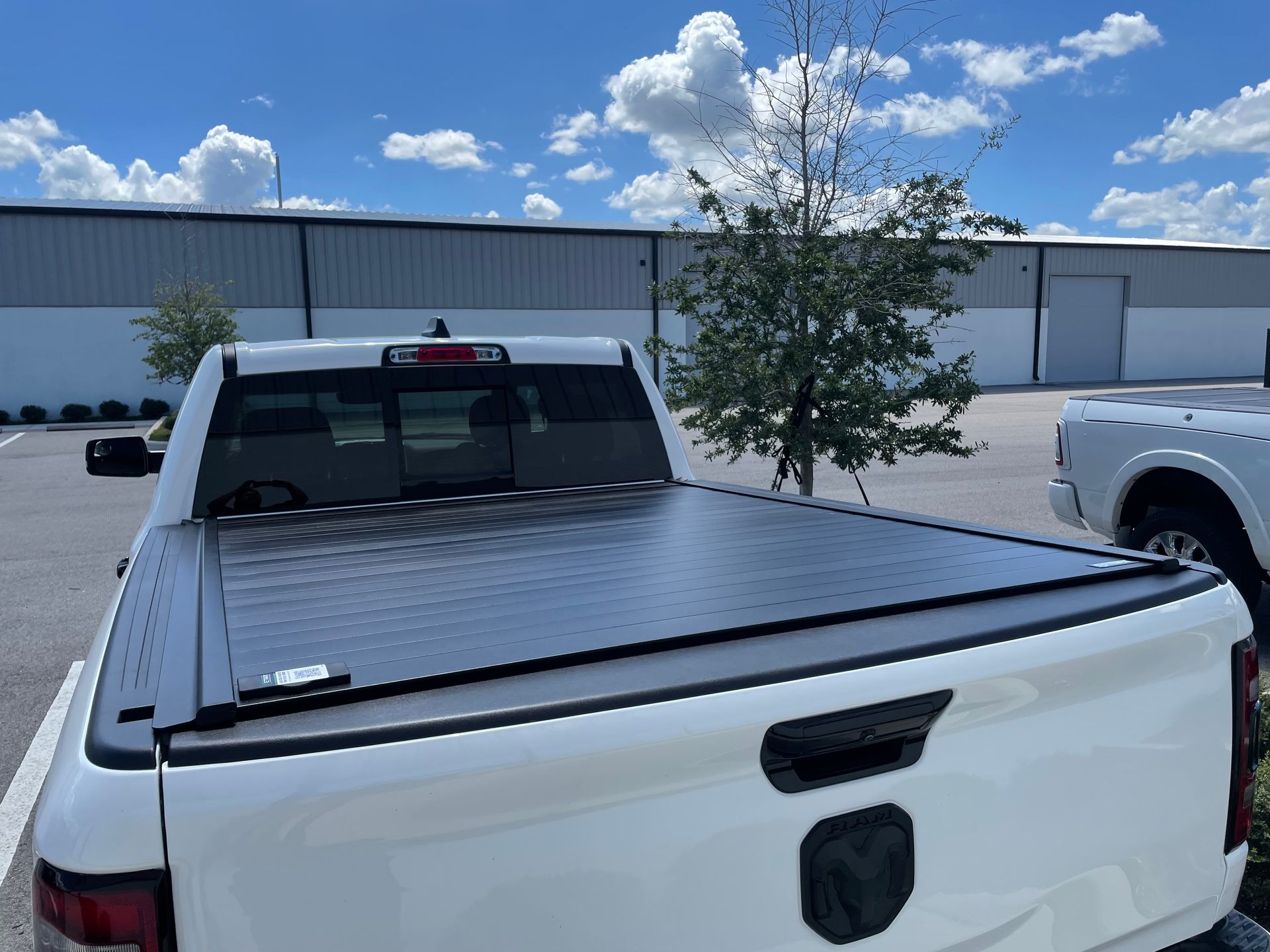 A white truck with a black bed cover is parked in a parking lot.