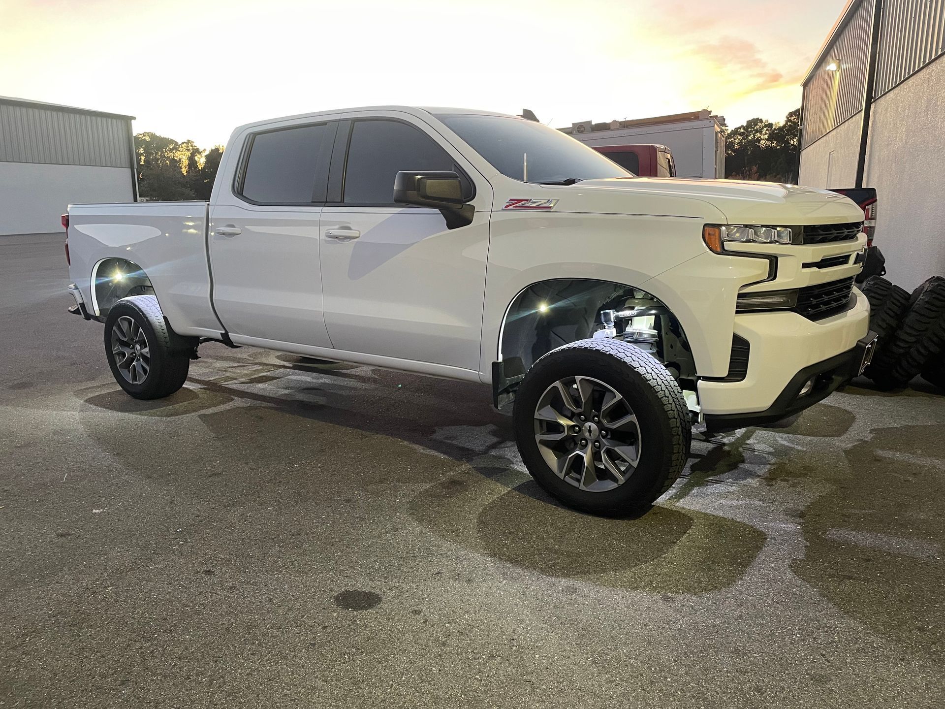A white truck is parked in a parking lot next to a building.