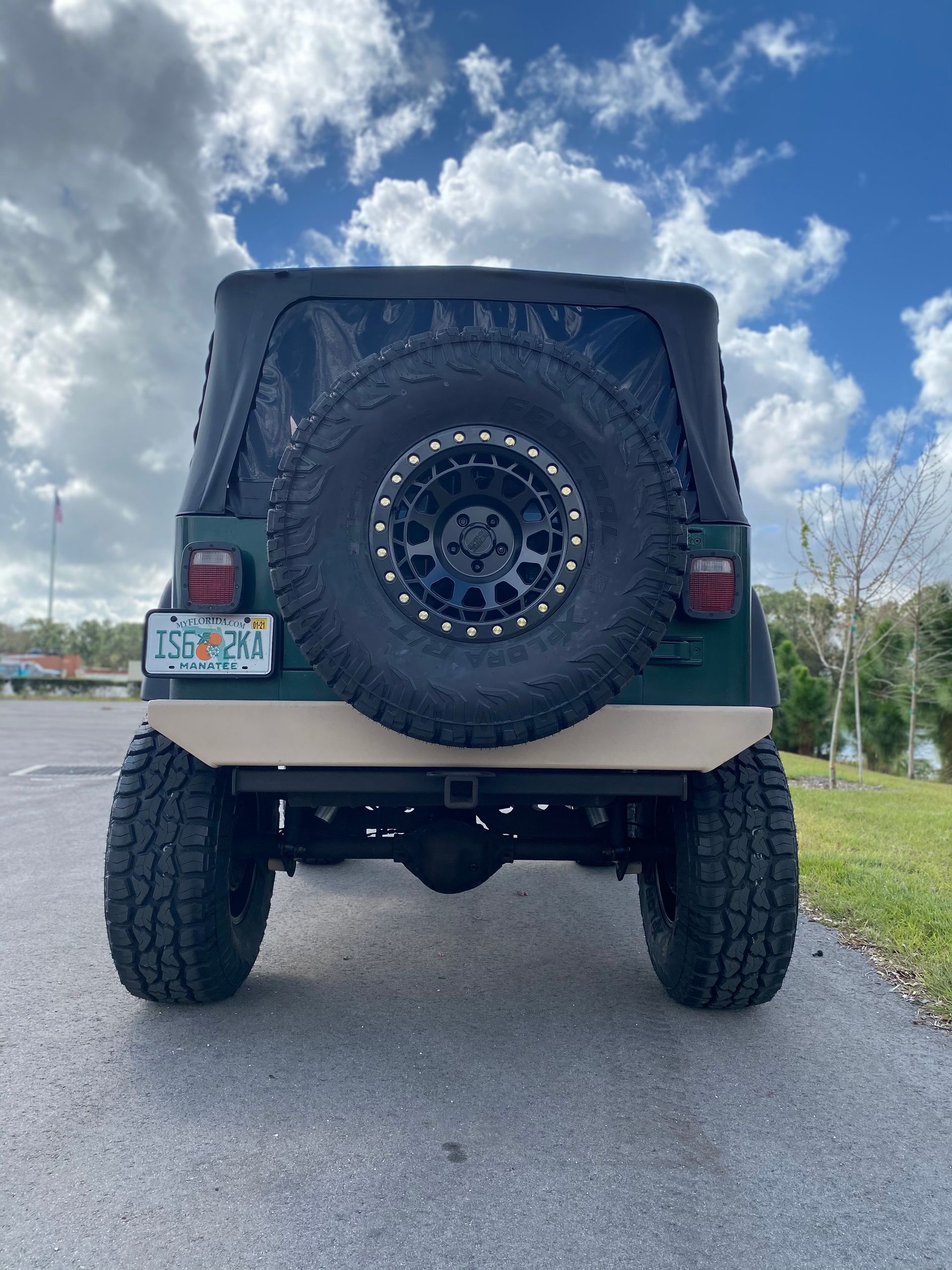 A green jeep is parked on the side of the road.