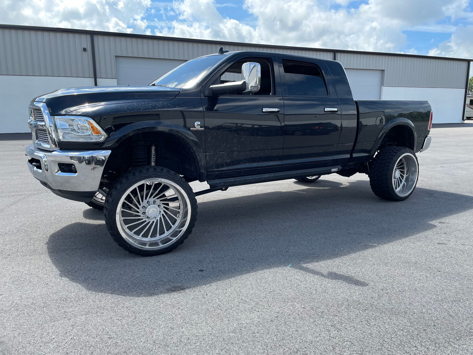 A black dodge ram truck is parked in a parking lot in front of a building.