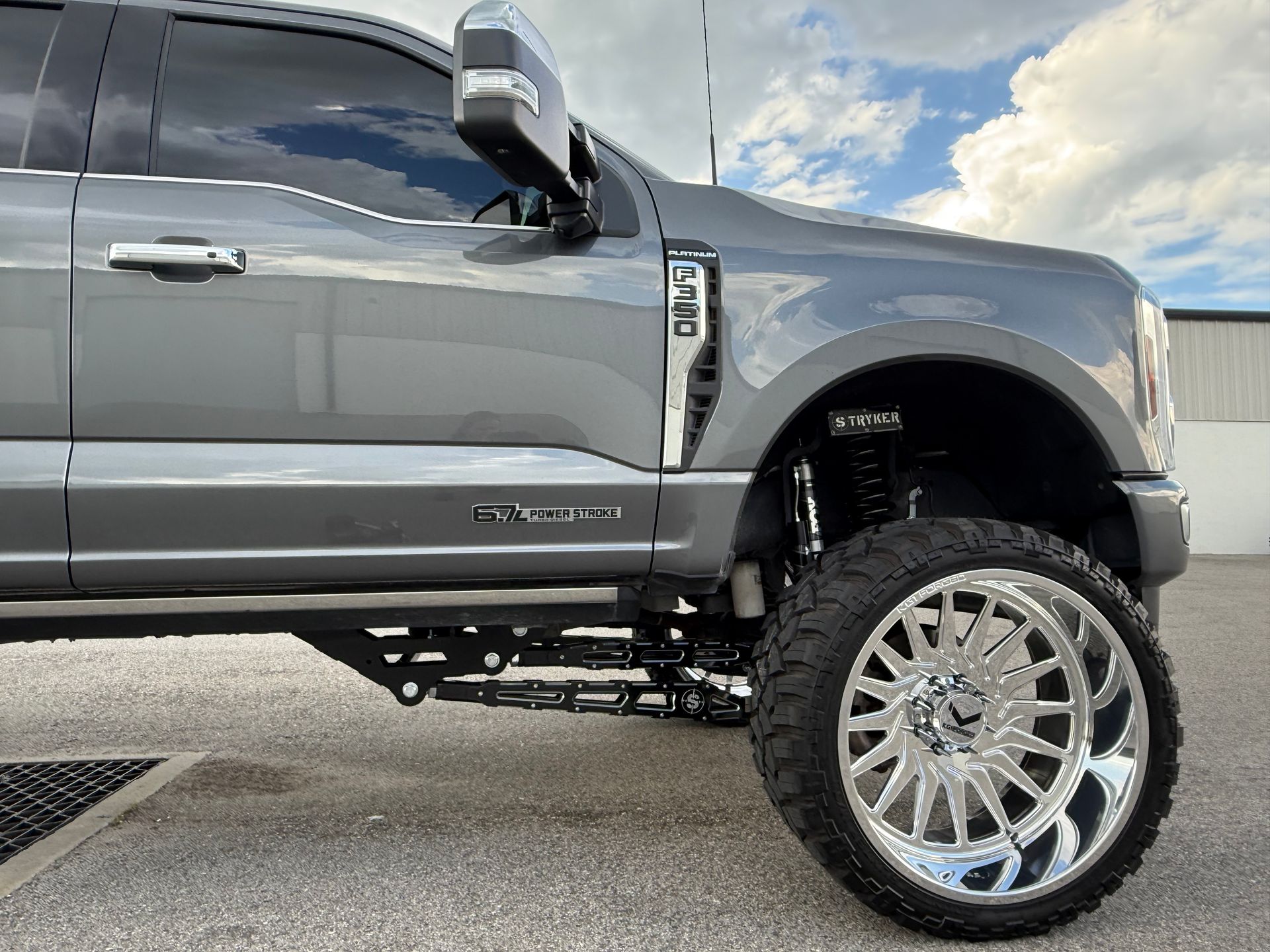 A gray truck with a lot of chrome wheels is parked in a parking lot.