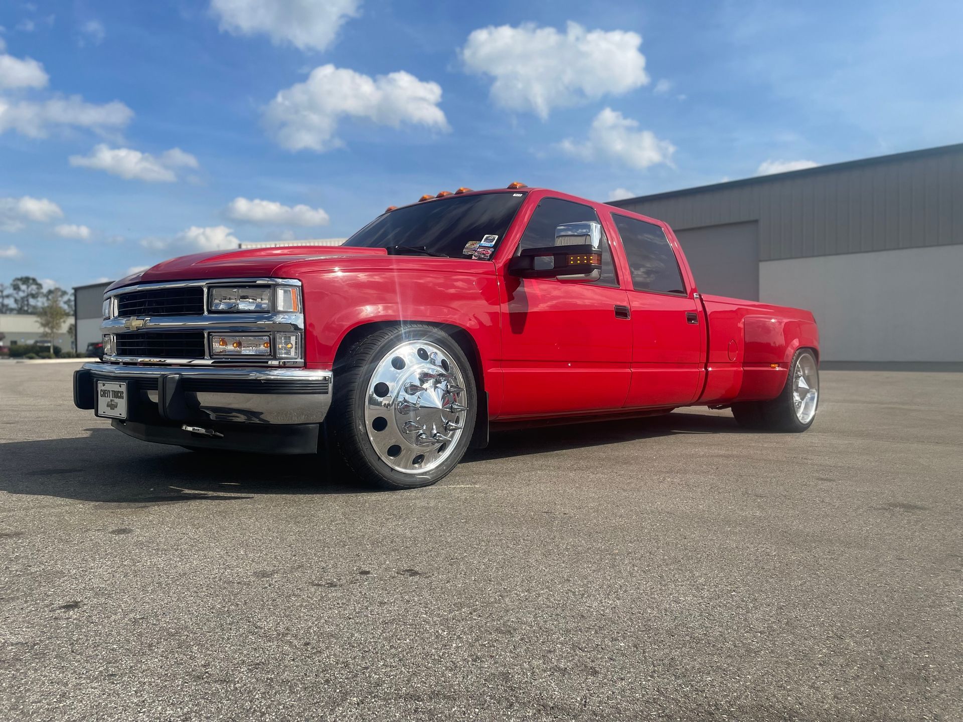 A red truck is parked in a parking lot in front of a building.