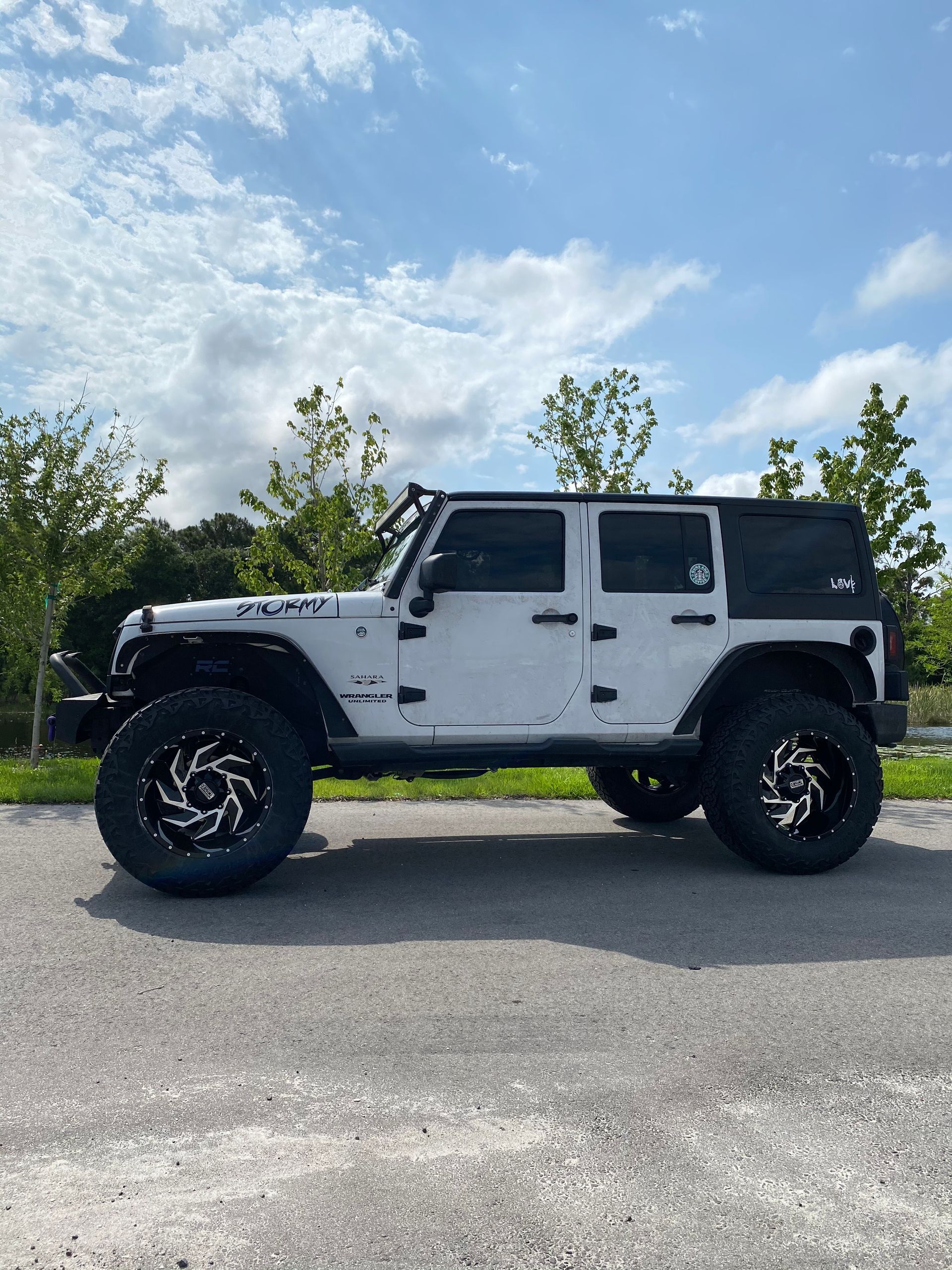 A white jeep is parked in a parking lot on a sunny day.