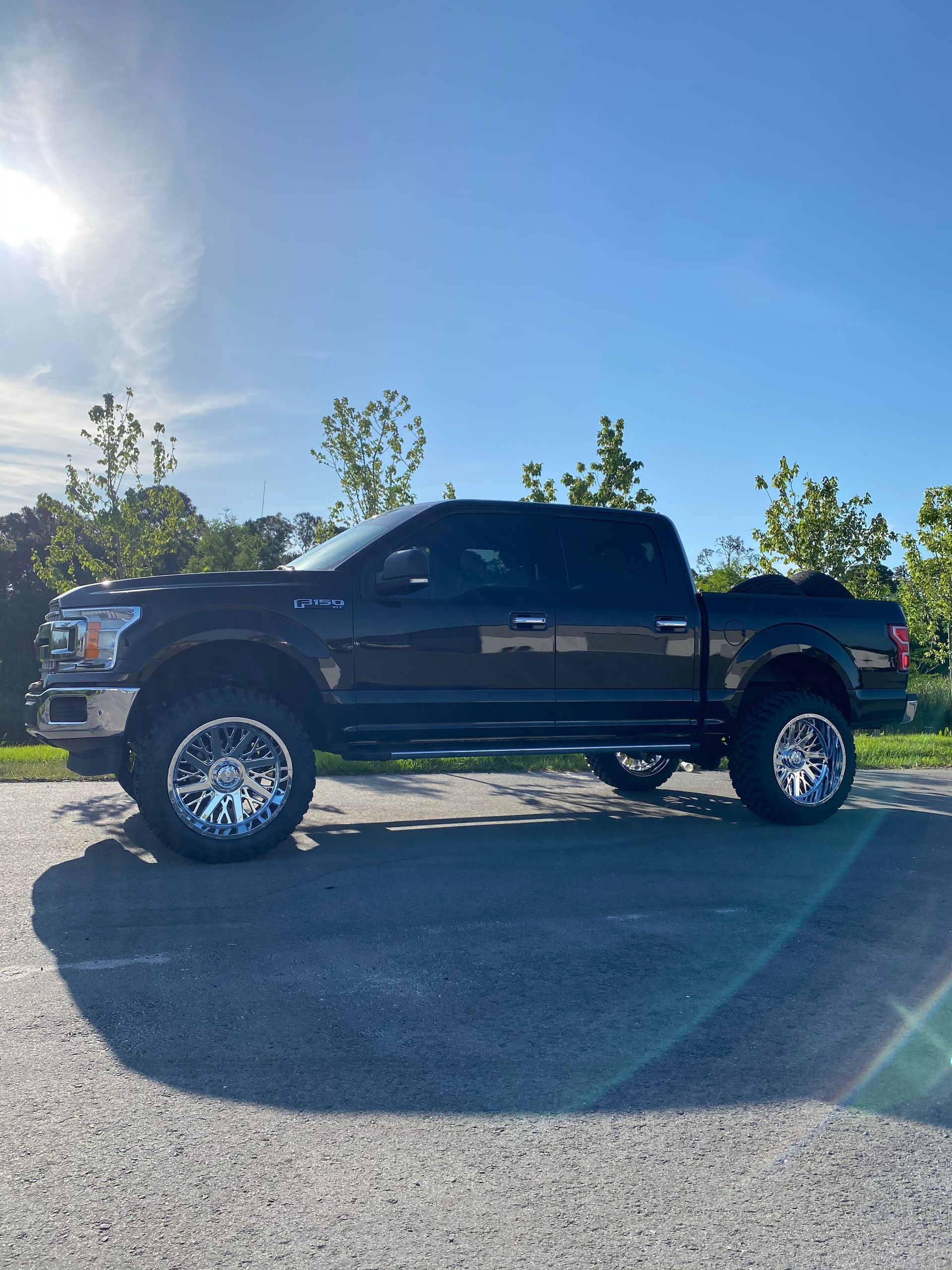 A black pickup truck is parked in a parking lot on a sunny day.