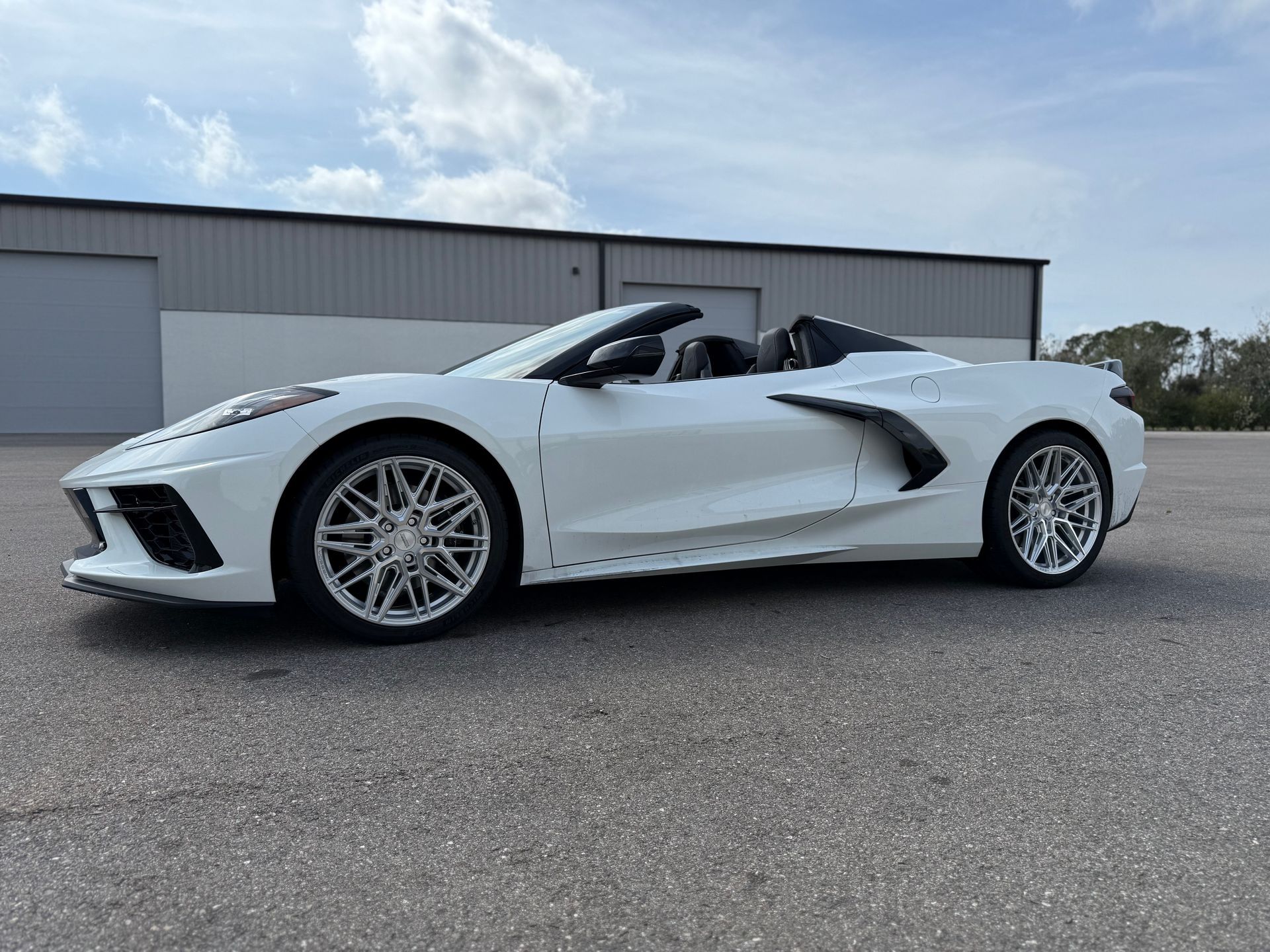 A man is driving a silver suv with a roof rack on top of it.