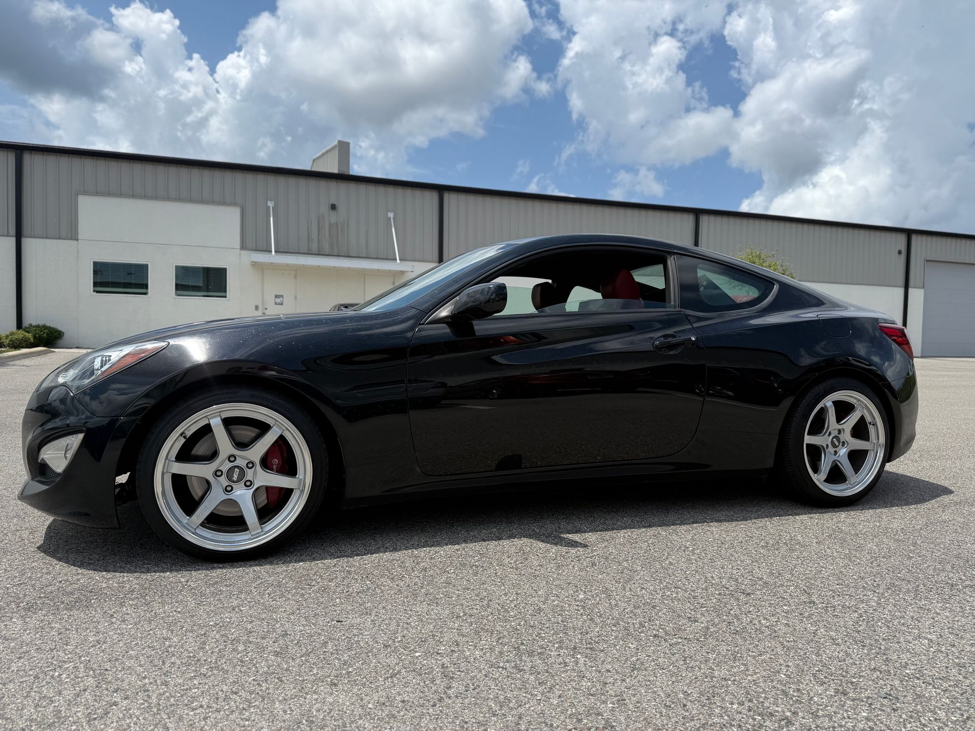 A black sports car is parked in front of a building.