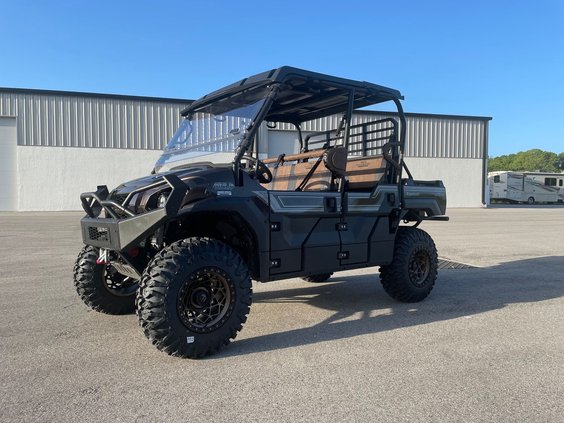 A kawasaki atv is parked in a parking lot in front of a building.