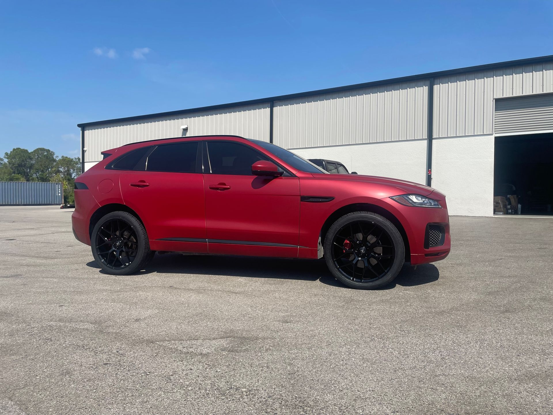 A silver bmw 3 series is parked in a parking lot in front of a building.