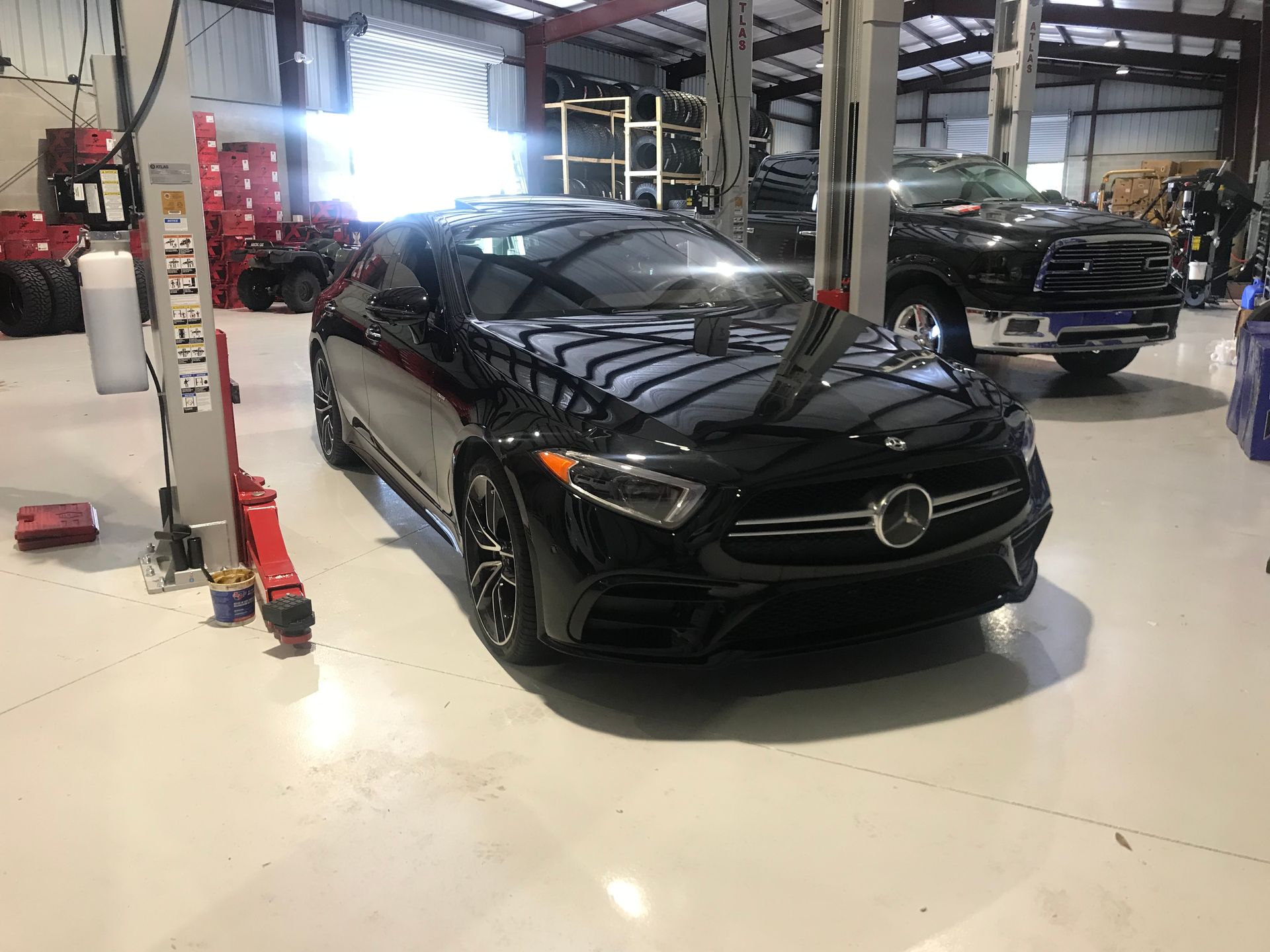A black mercedes benz is parked in a garage on a lift.