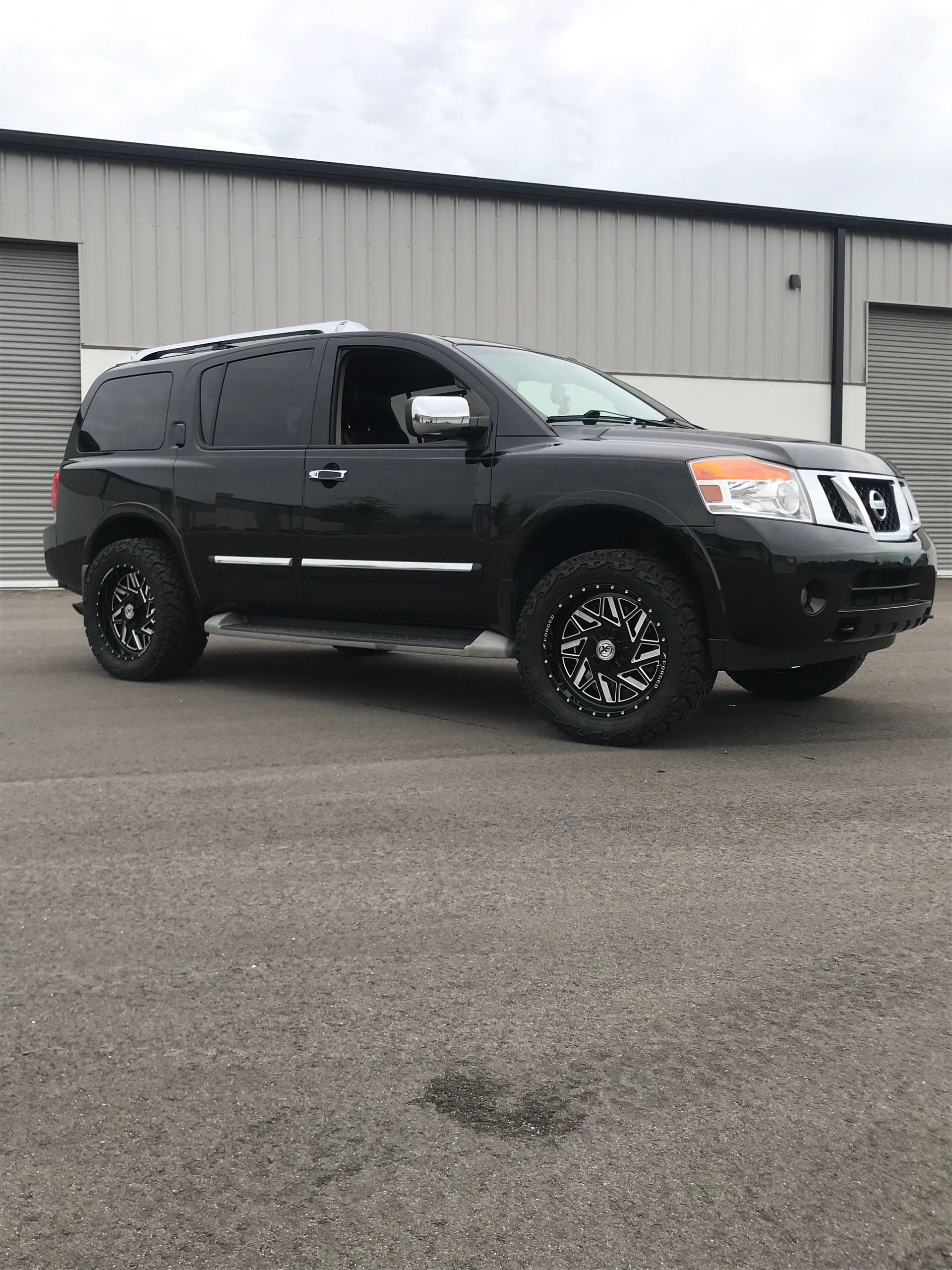 A black suv is parked in front of a building.