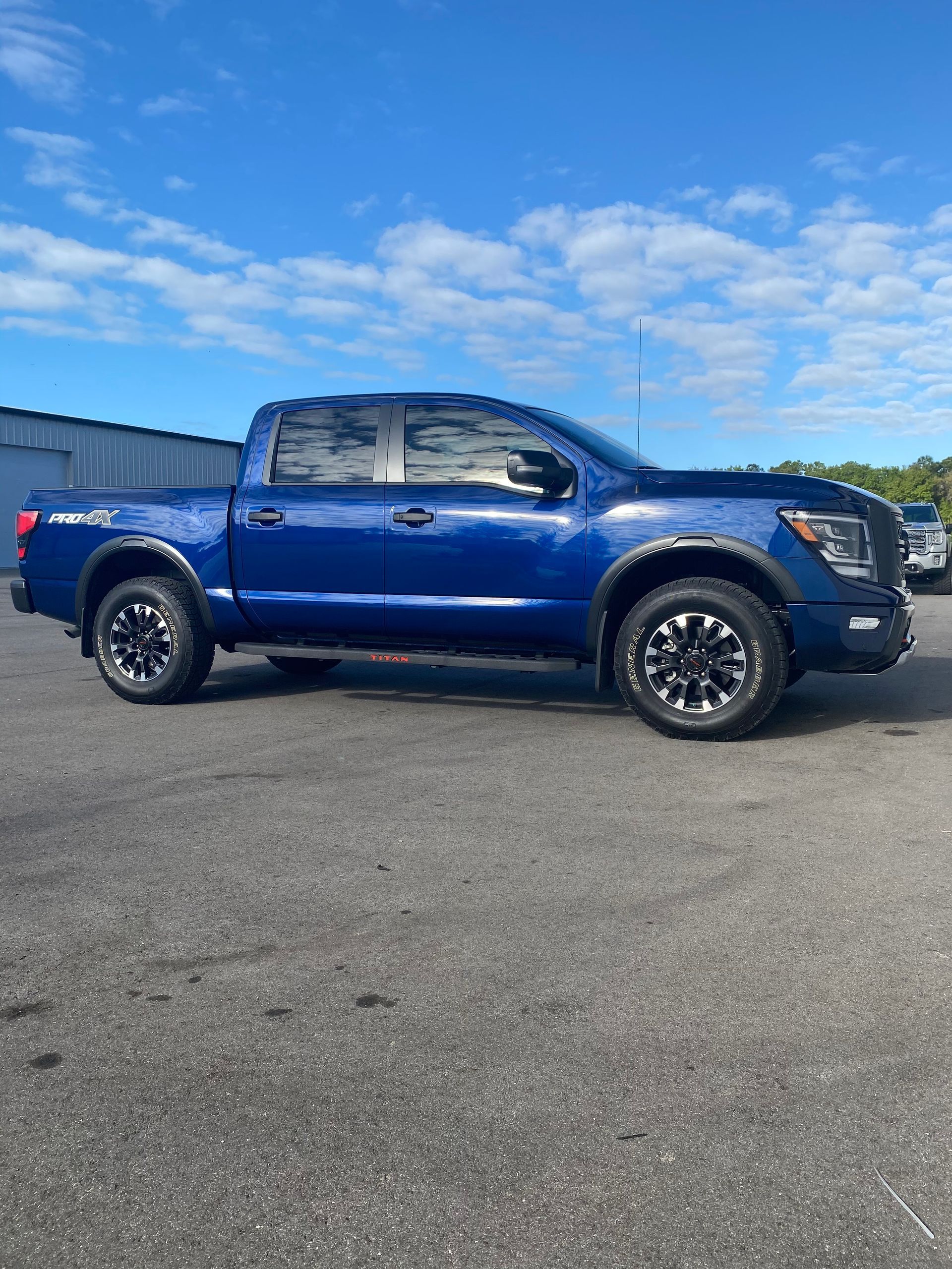 A blue nissan titan truck is parked in a parking lot.