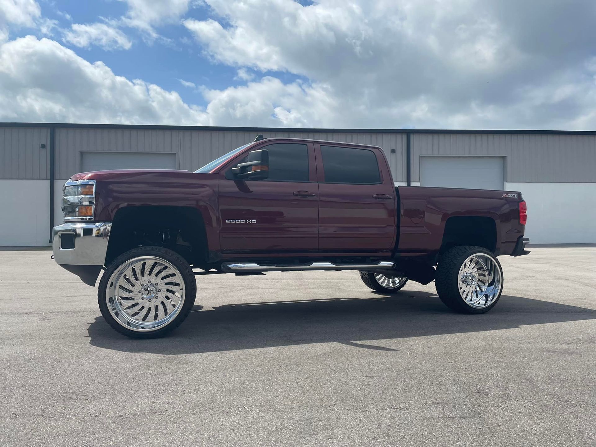 A burgundy truck is parked in front of a building.