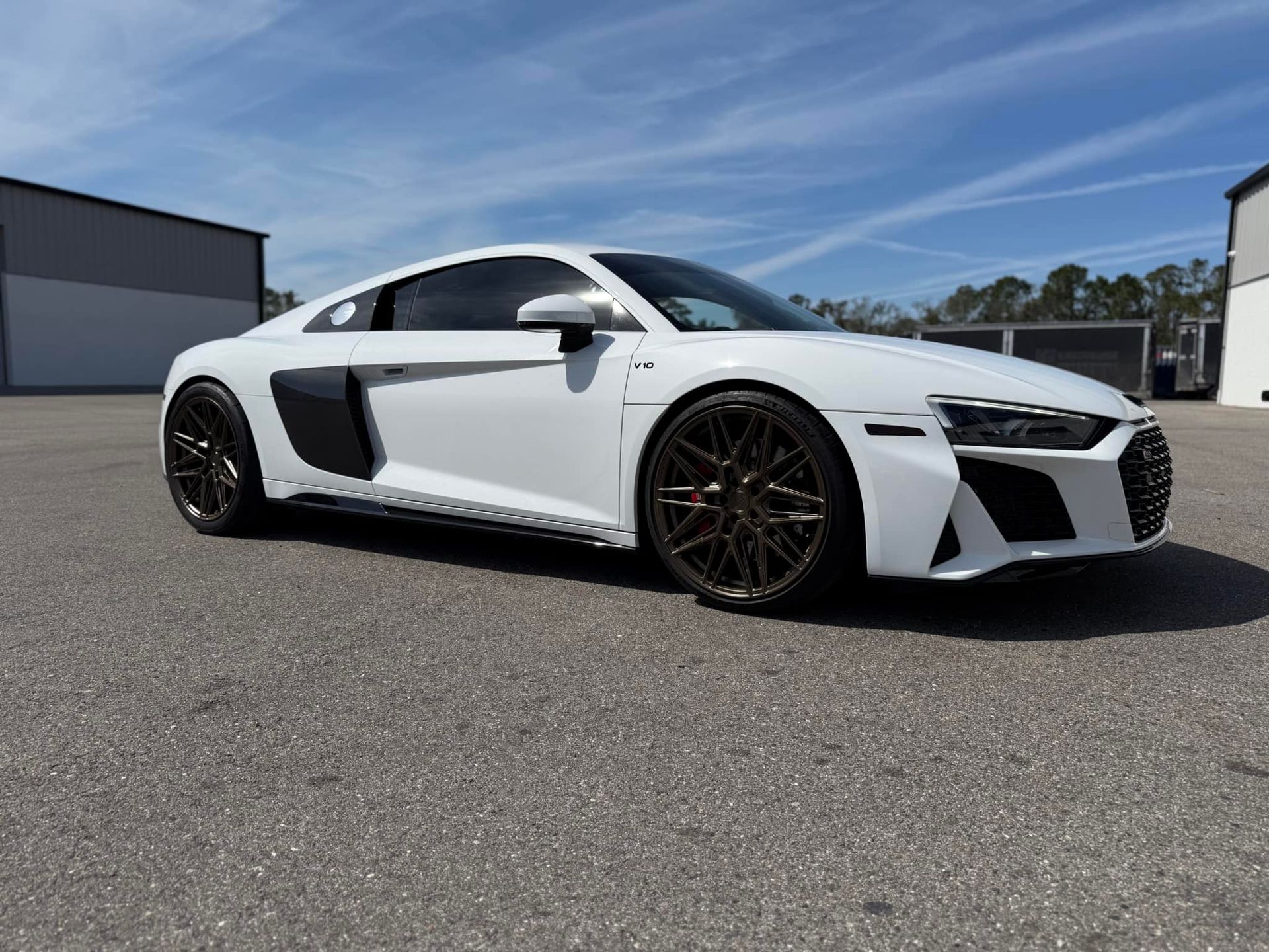 A white audi r8 coupe is parked in a parking lot.