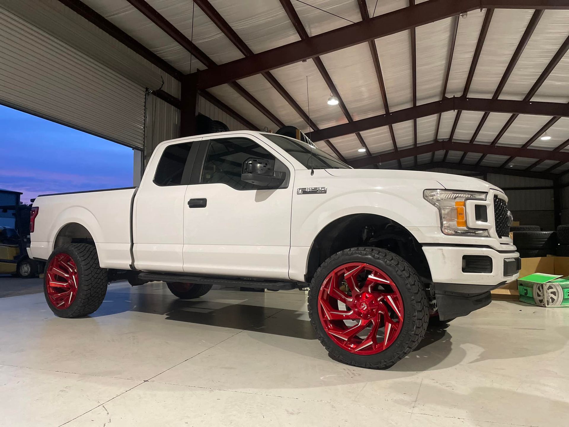 A white truck with red wheels is parked in a garage.