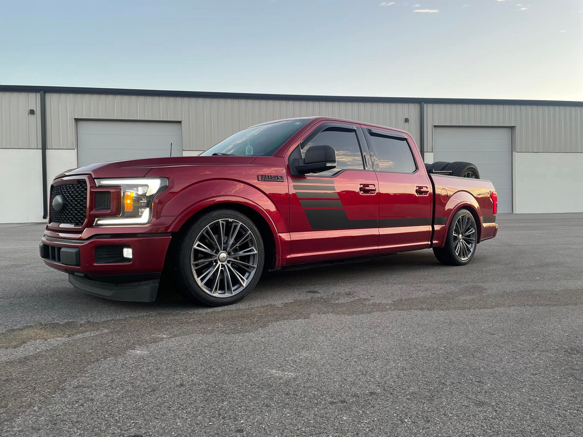 A red ford f150 truck is parked in front of a building.