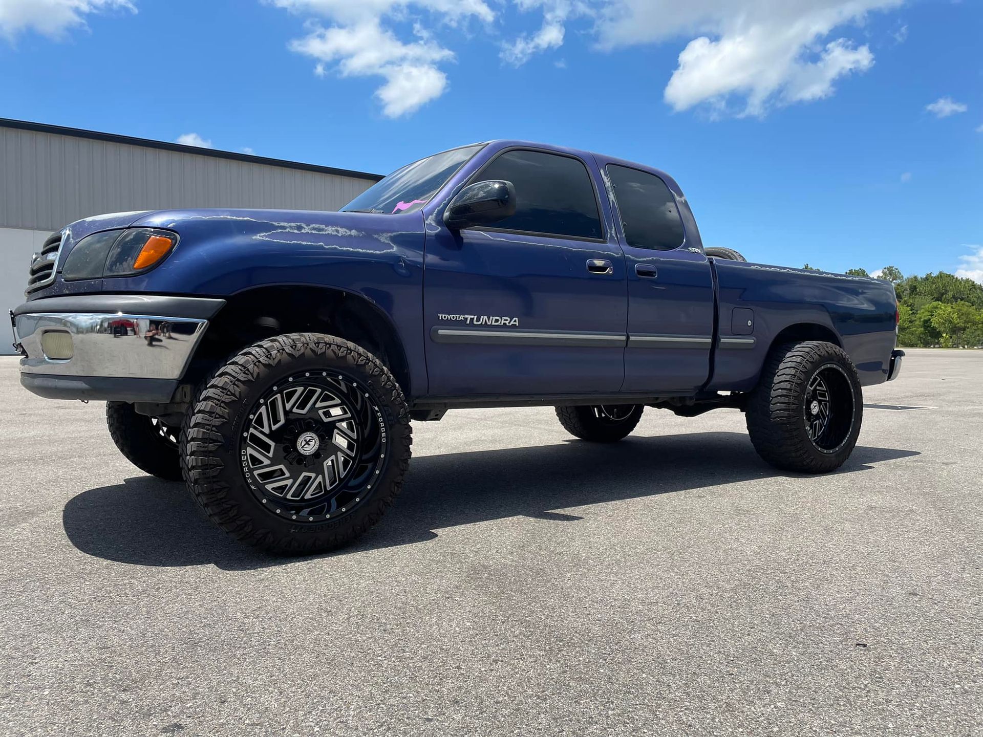 A blue truck is parked on the side of the road.