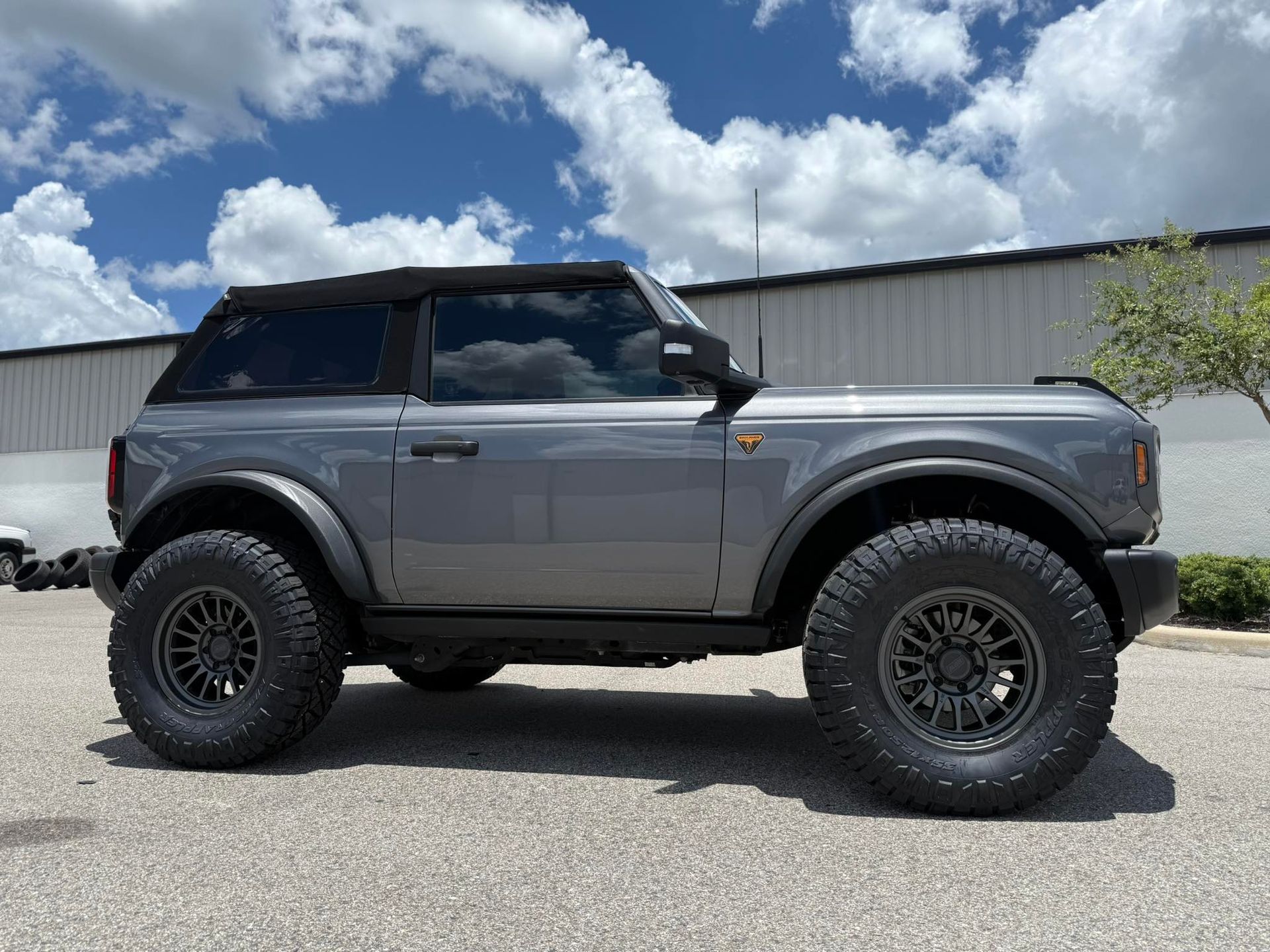 A gray ford bronco is parked in front of a building.