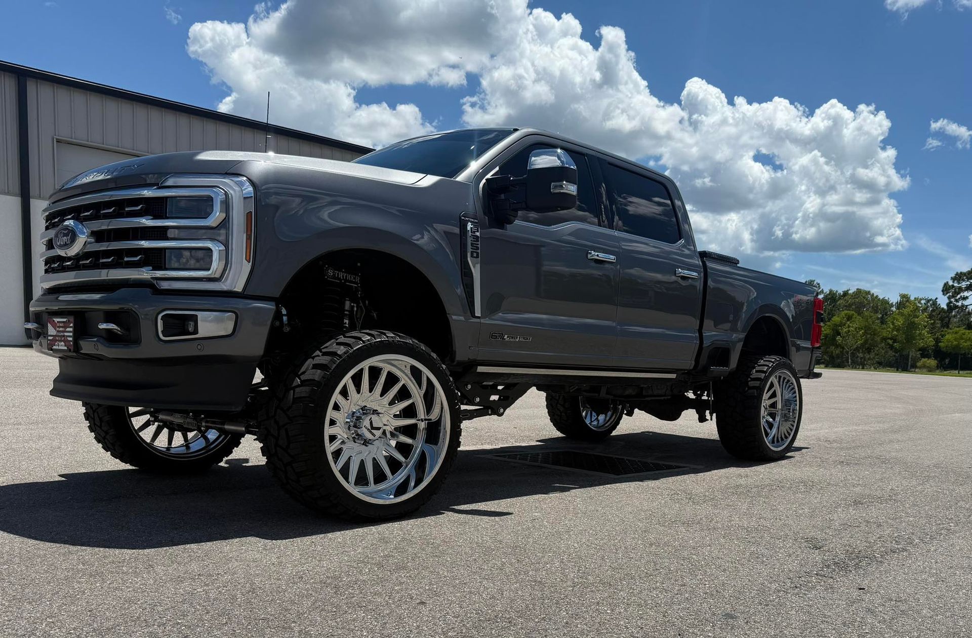A gray ford f250 super duty truck is parked in front of a building.